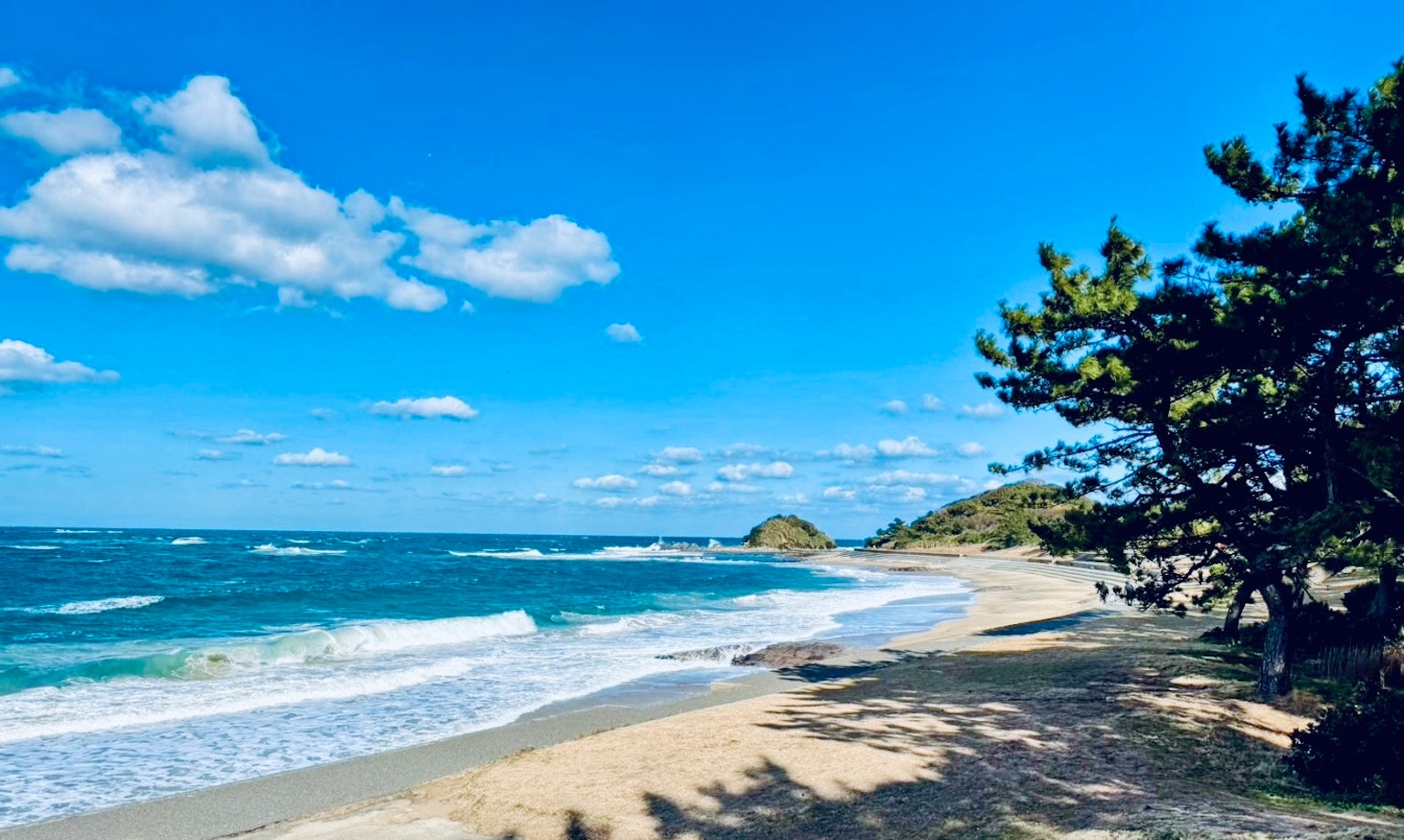 ทิวทัศน์ชายหาดพร้อมมหาสมุทรสีน้ำเงินและเมฆสีขาว