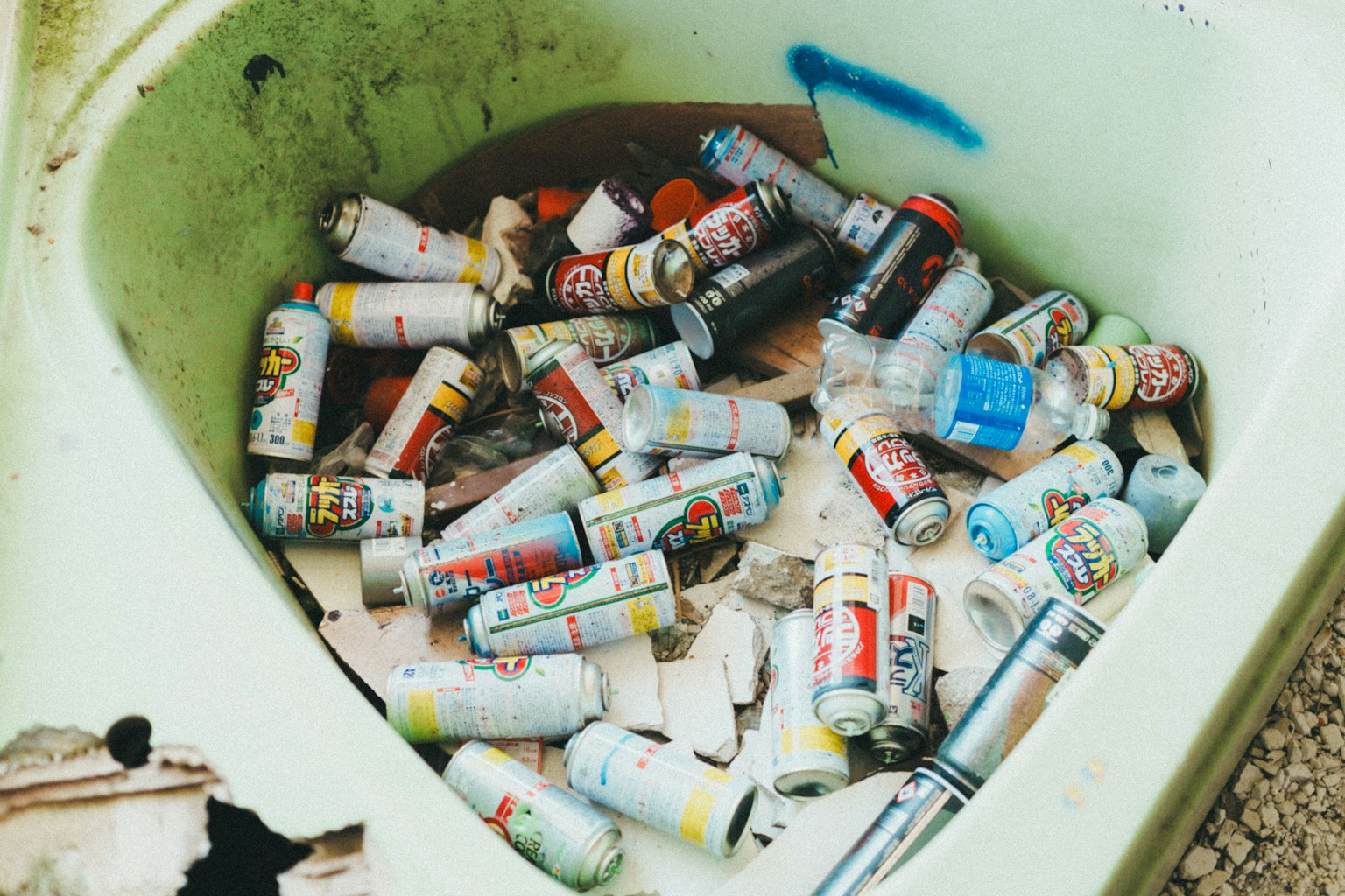 Colorful spray cans scattered in a green bathtub