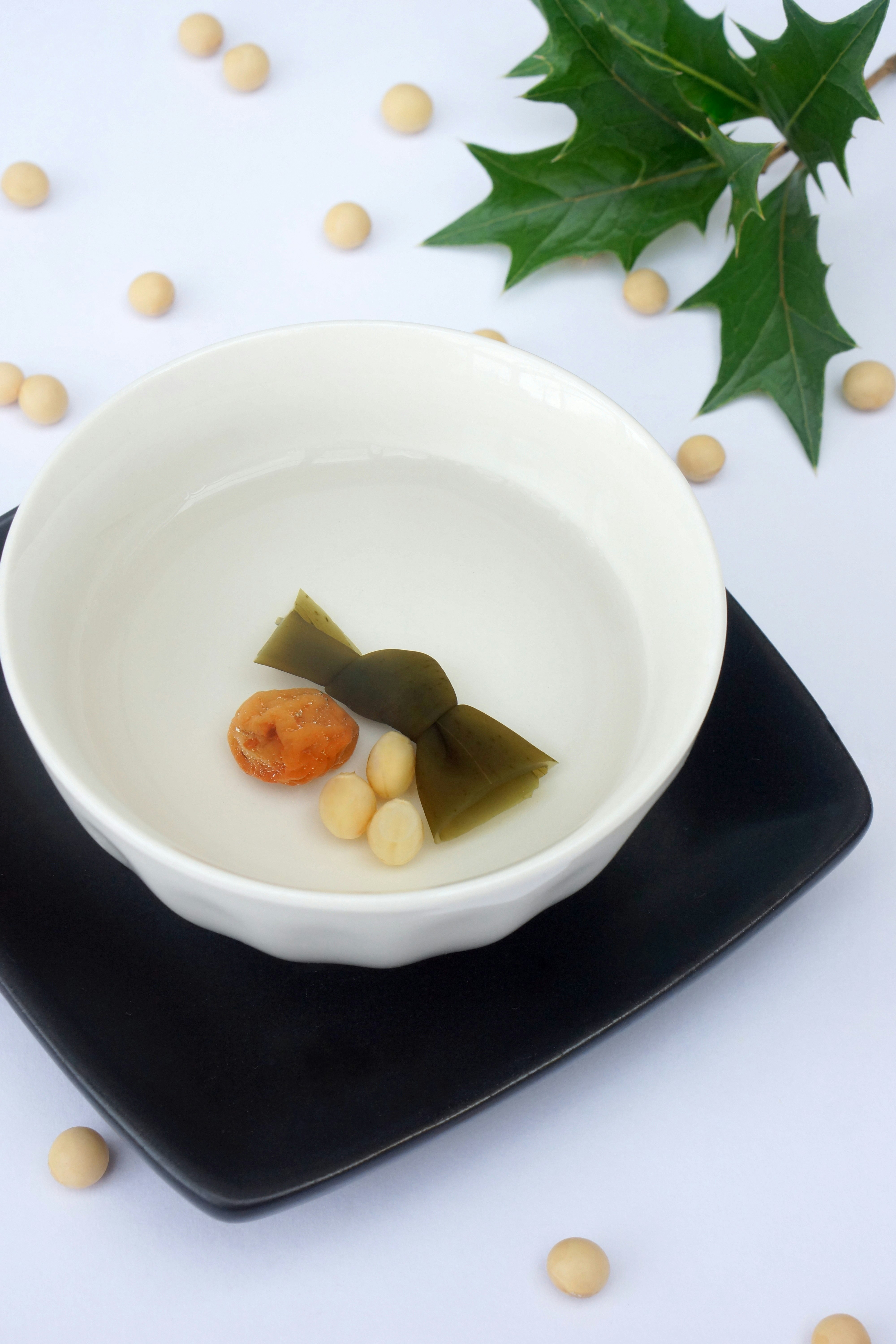 白い皿に盛られた透明なスープに昆布と豆が入っている