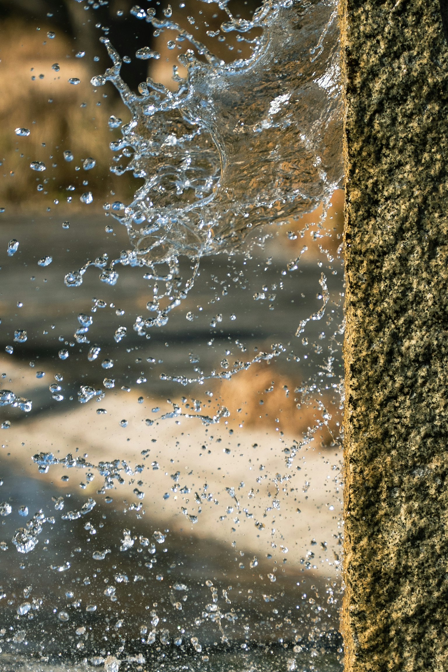Primo piano di acqua che schizza vicino a un pilastro di pietra