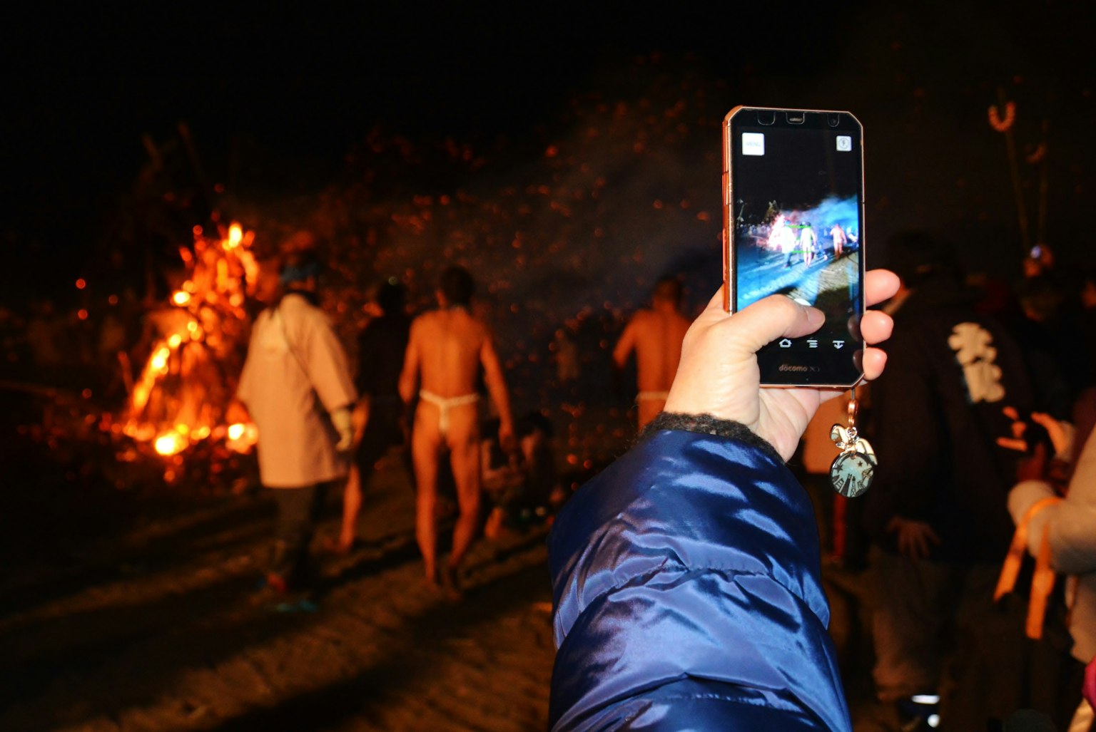 Reunión de personas por la noche con fuego de fondo y fotografía con teléfono inteligente