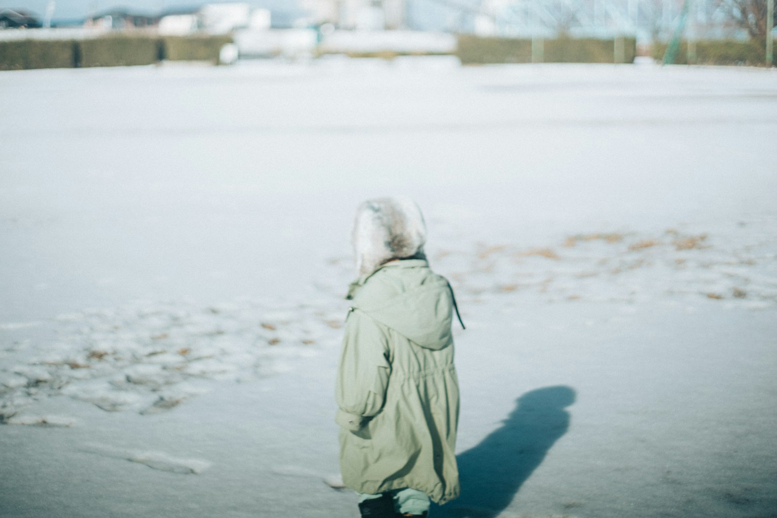 穿着绿色外套在雪中行走的孩子