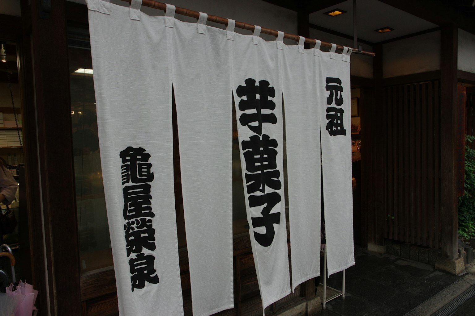 Traditionelle japanische Geschäftsfassade mit weißem Noren und schwarzen Buchstaben