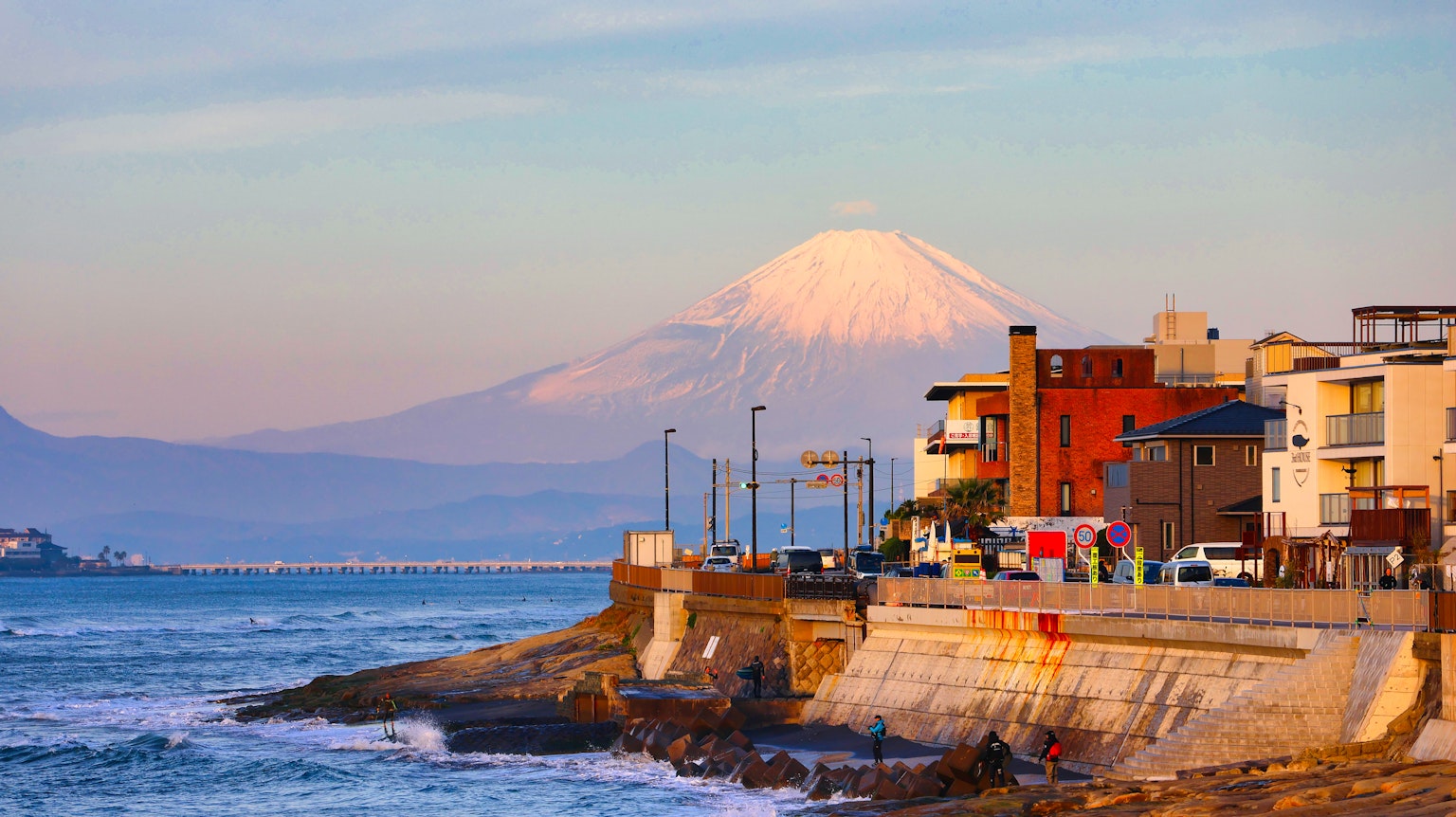 Vue côtière avec le mont Fuji en arrière-plan et des bâtiments colorés