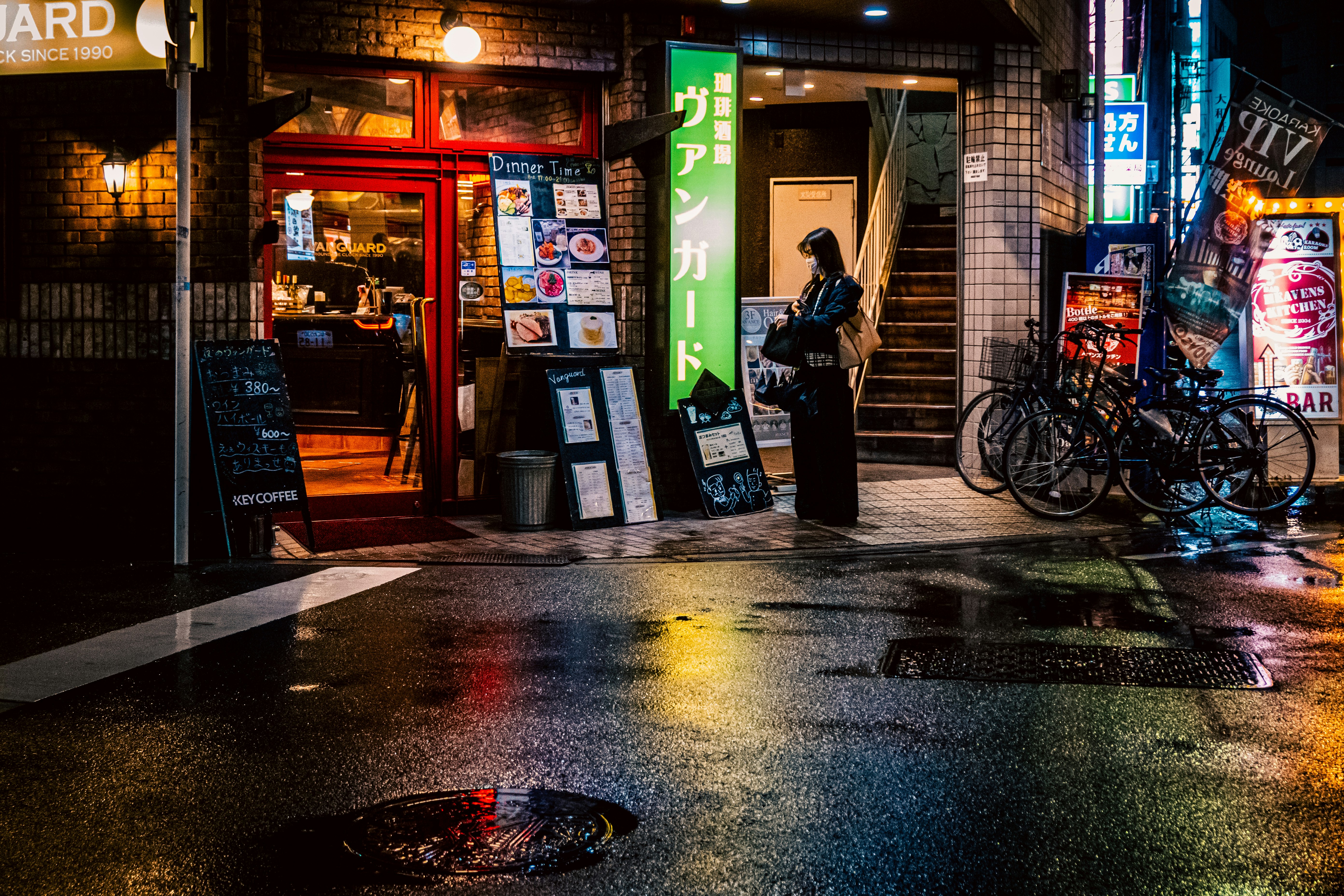 夜の路地に並ぶ看板と自転車のある飲食店の入口