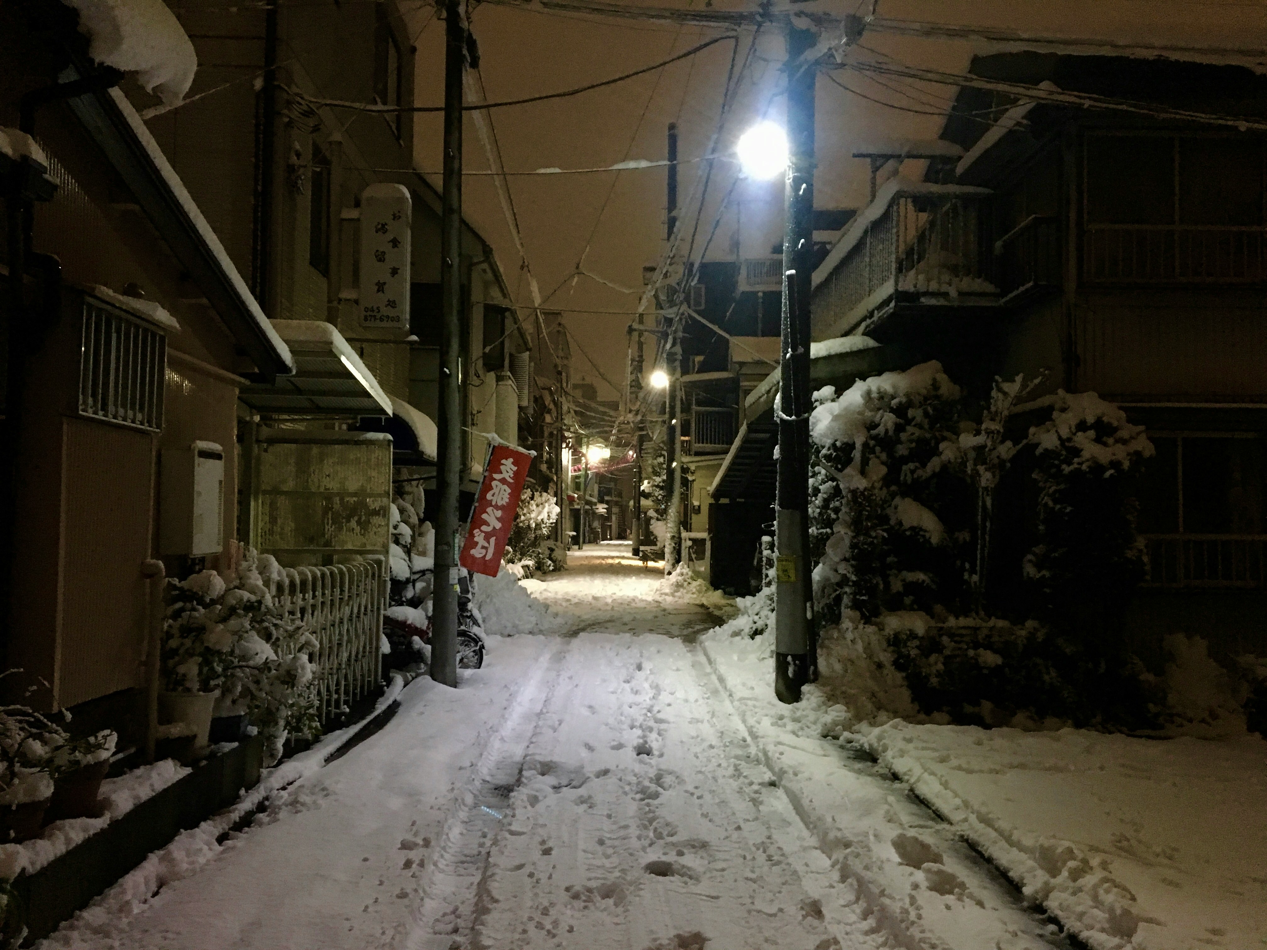 雪の路地に並ぶ家々と街灯の光