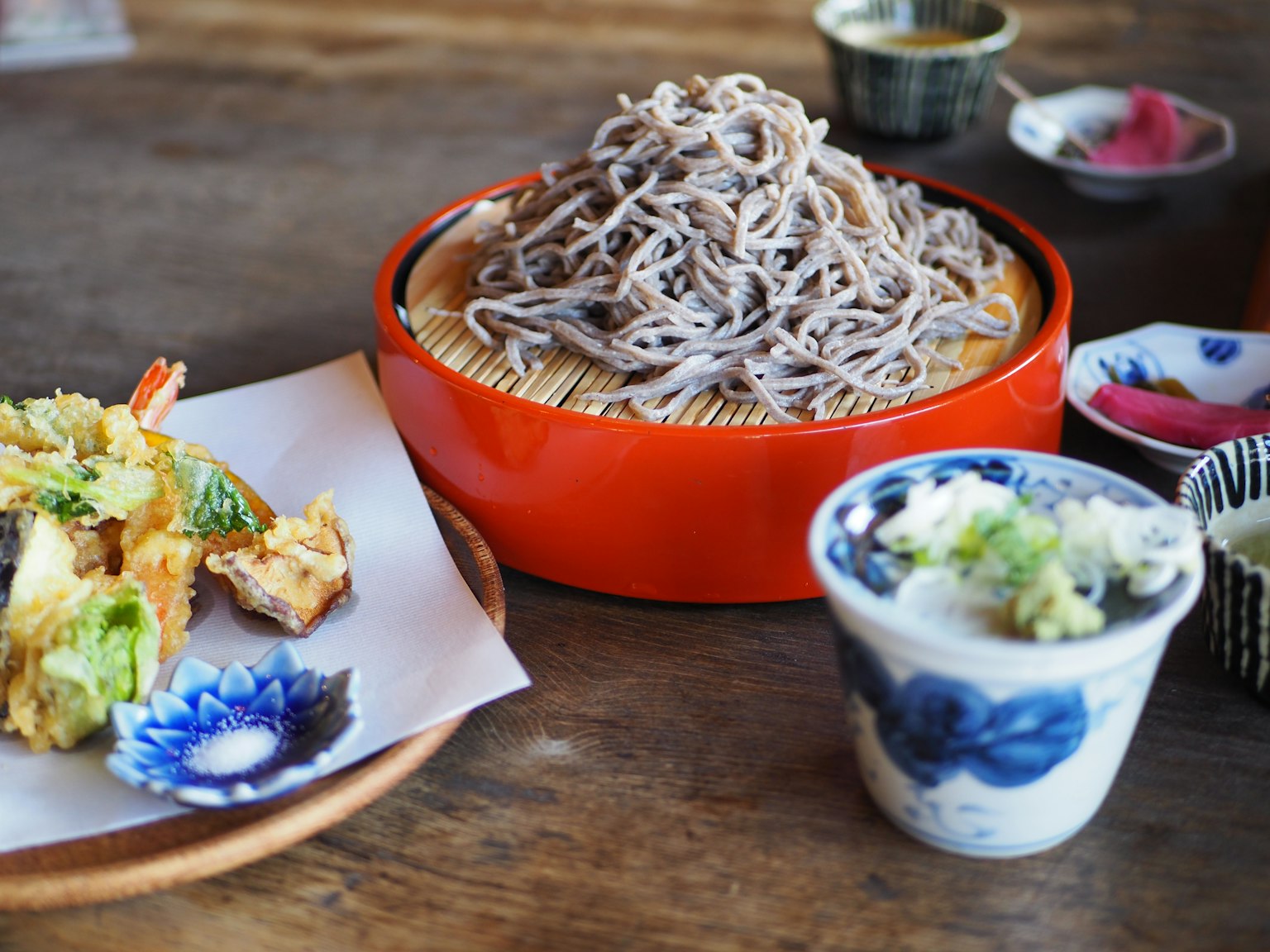 Soba-Nudeln in einer roten Schüssel mit Tempura auf einem Teller