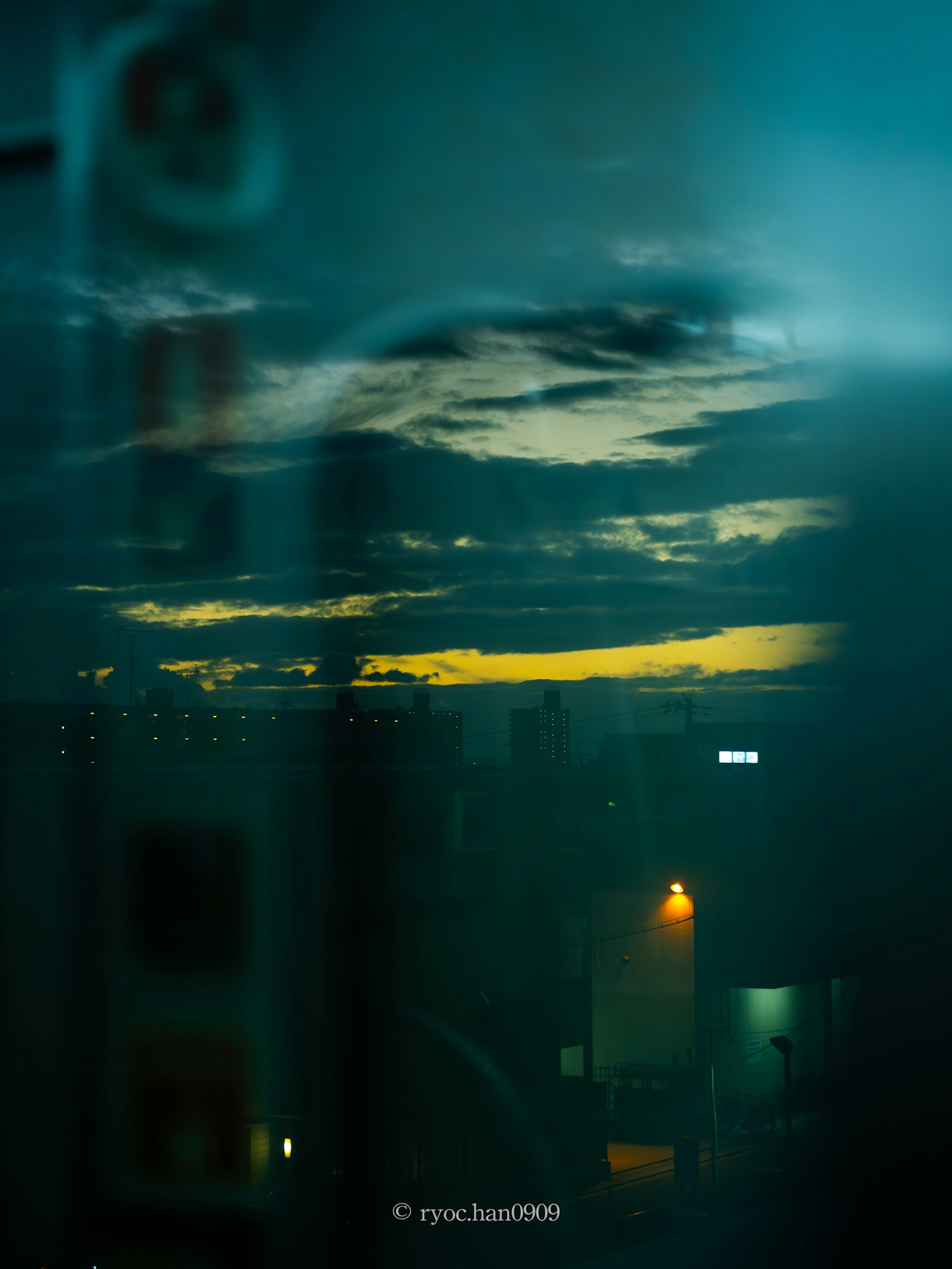 Ciel nocturne avec des nuages illuminés par une lumière bleue et des lumières de la ville