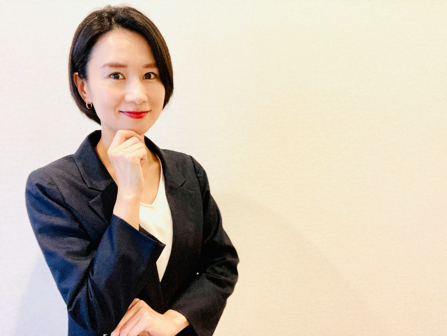 一位穿着商务套装的女性微笑着，手托着下巴