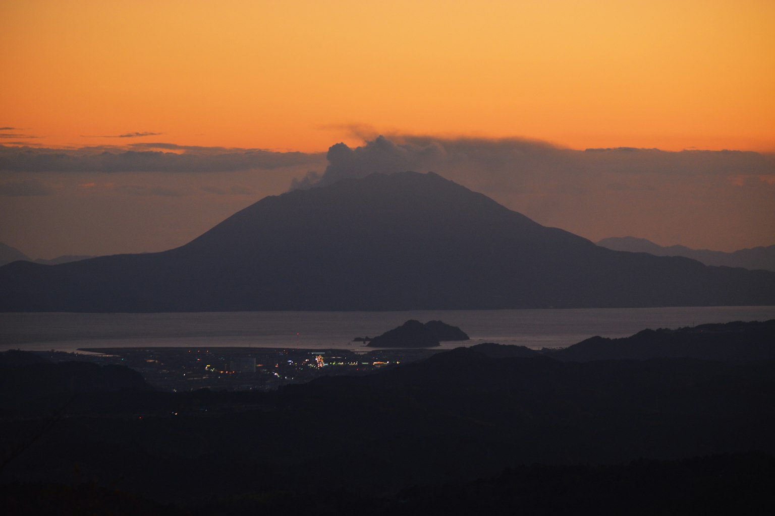 夕陽下火山的輪廓和前景的小島