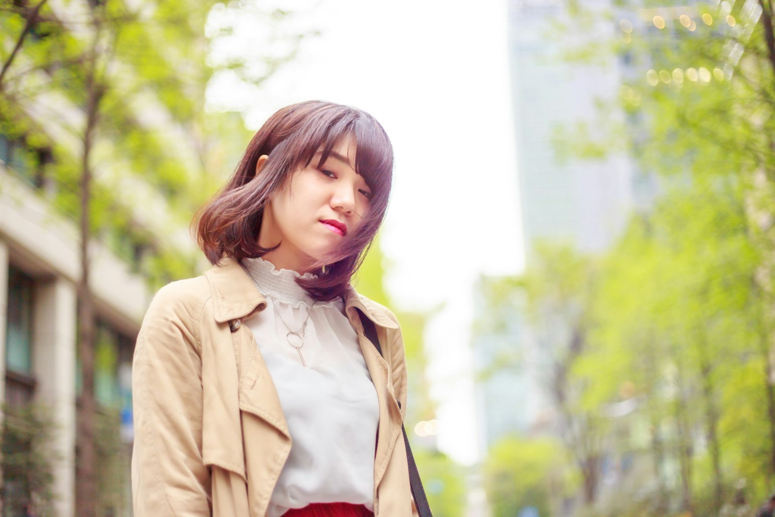 微笑的女性在綠色街樹之間的肖像