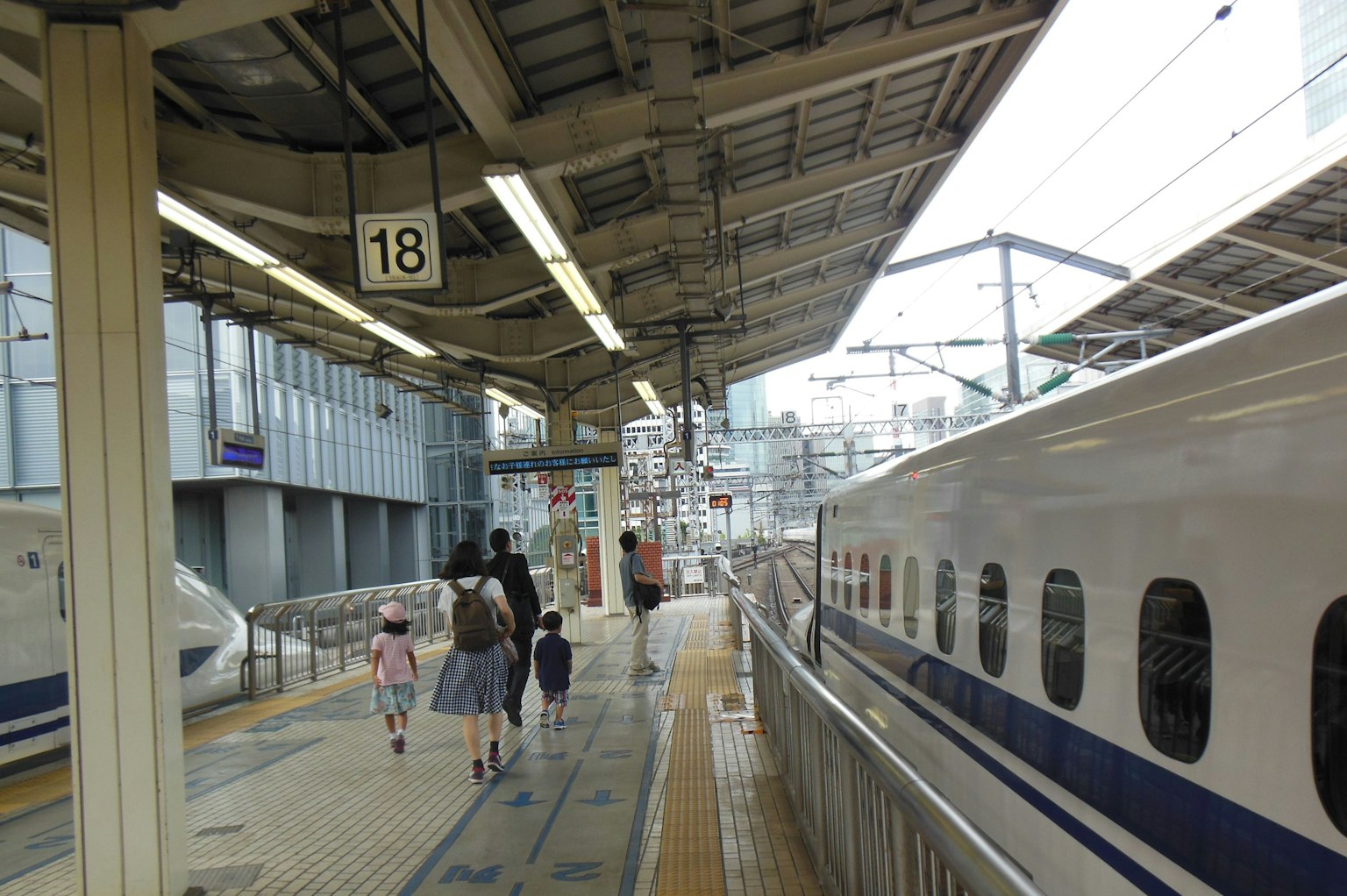 Famille marchant sur le quai 18 d'une station de Shinkansen avec un train garé