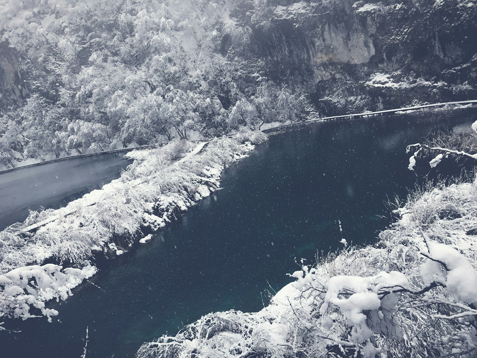 Snow-covered riverbank with surrounding snowy mountains