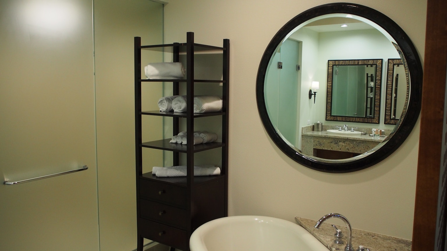 Design semplice e moderno di un bagno con specchio rotondo e scaffale