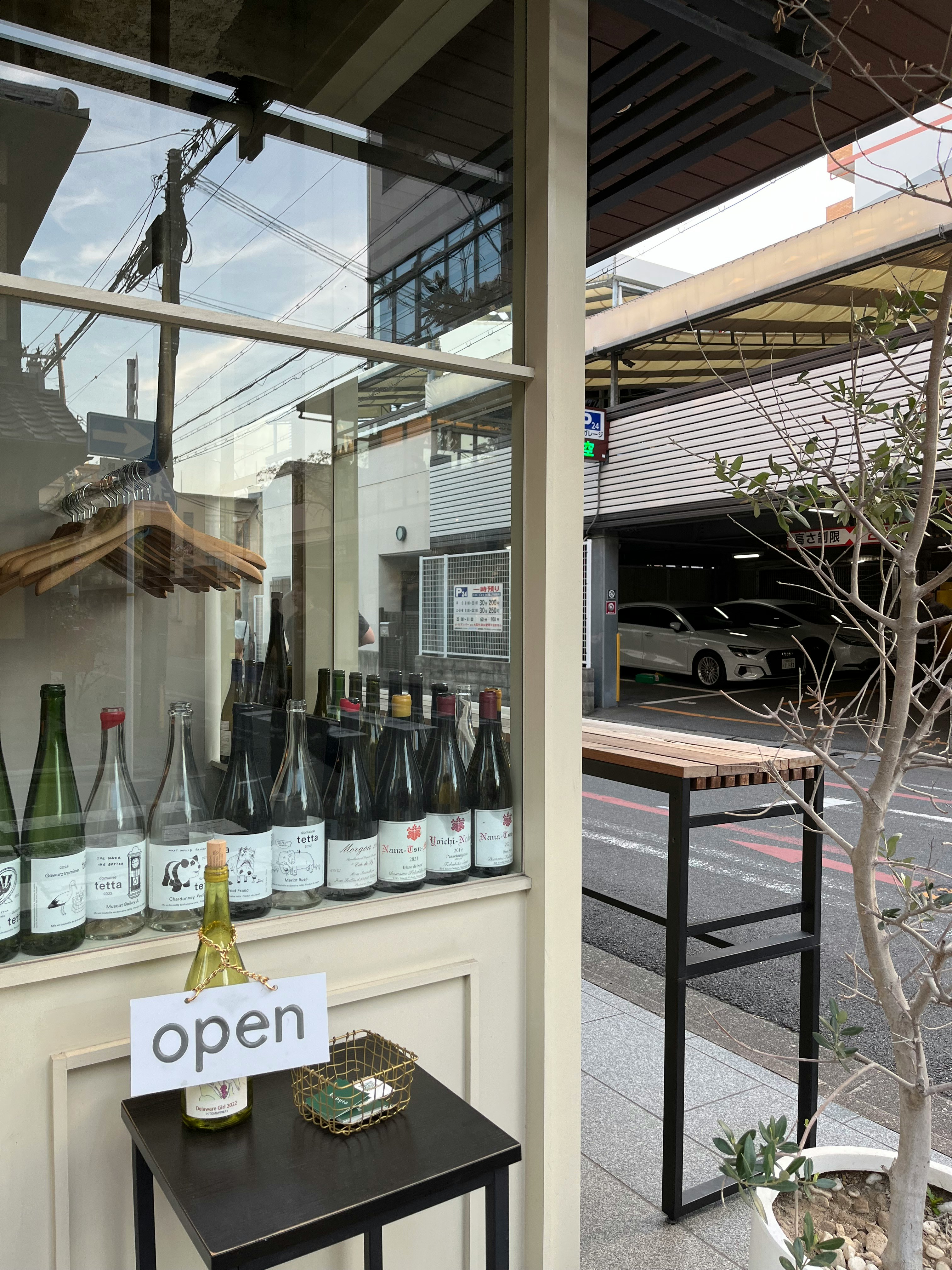 ガラス越しの店内に並ぶボトルと「open」看板のある小さな店舗入口