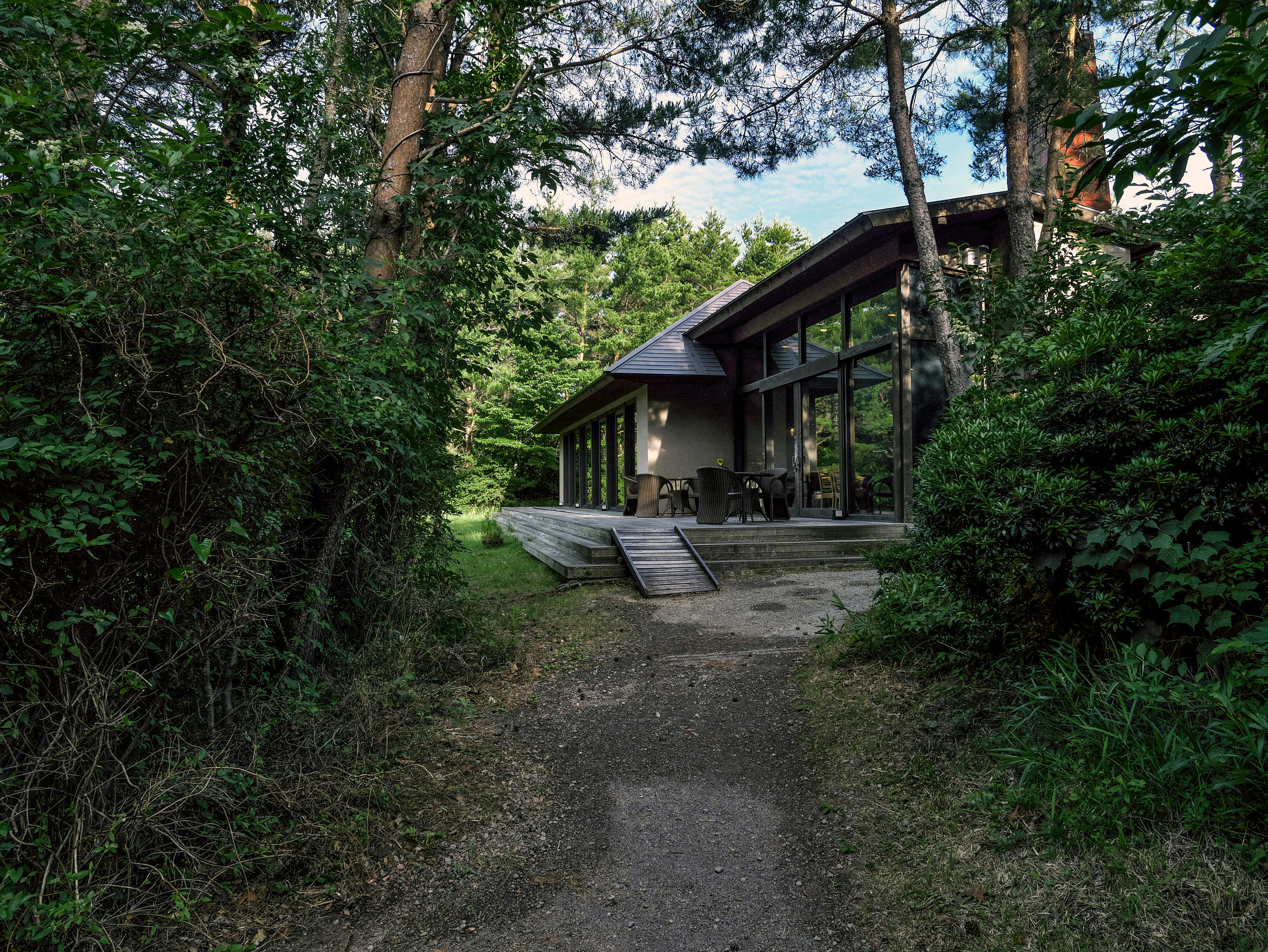 森に囲まれた木造の小屋とベンチのある中庭