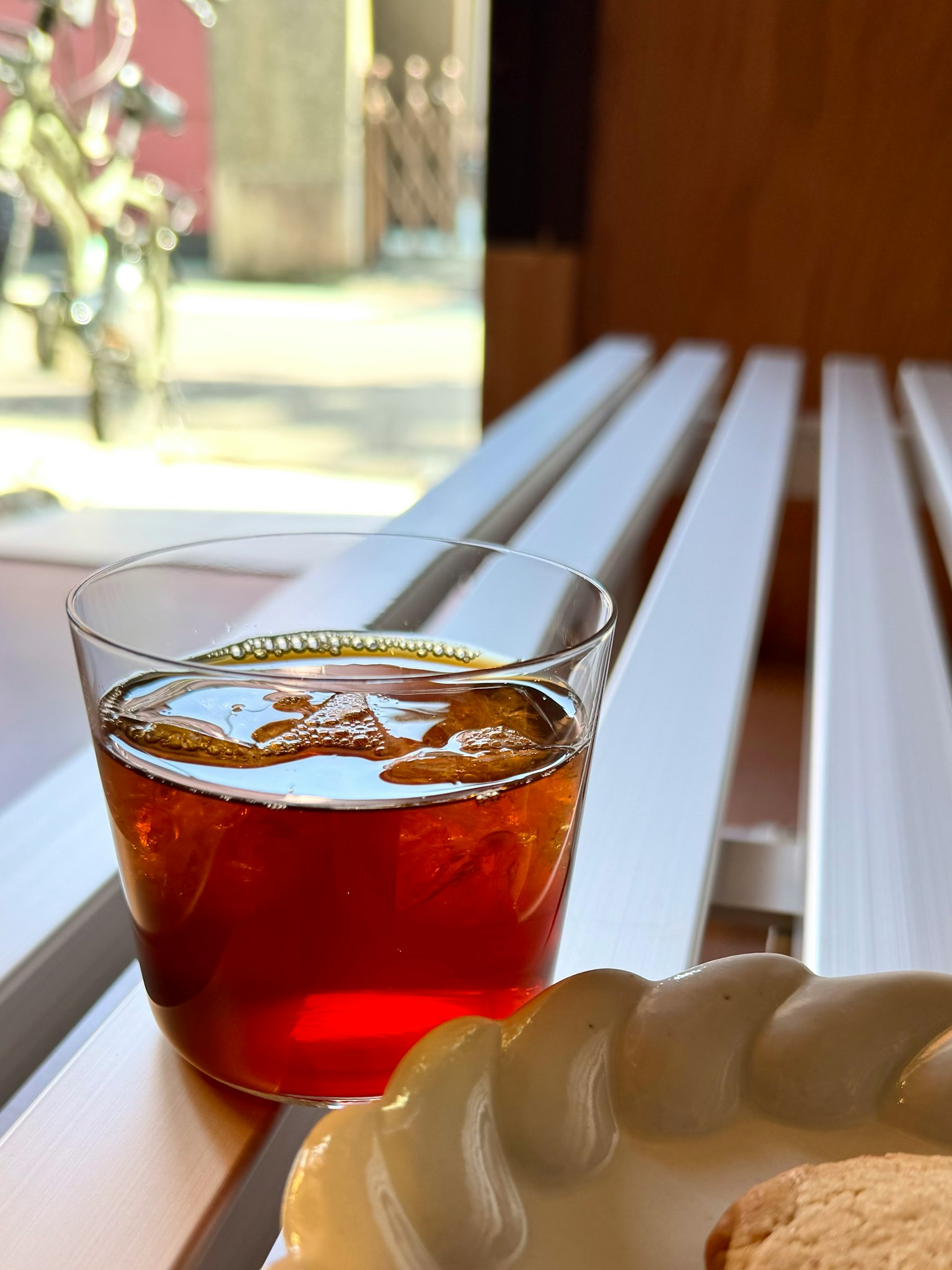 Ein Glas Eistee auf einem Tisch mit einem Teller Keksen