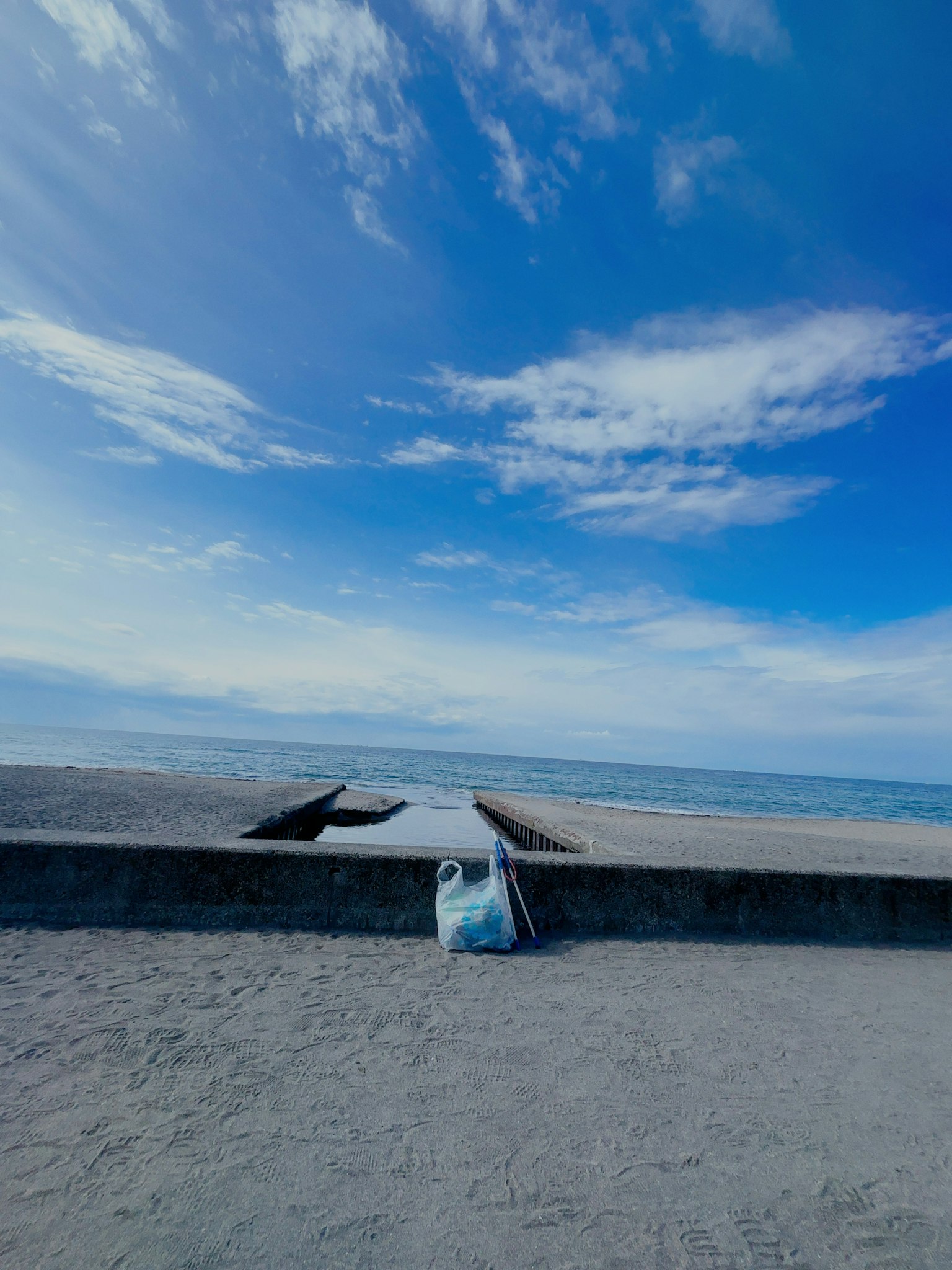 Scenic view of blue sky and ocean with sandy beach and concrete pier