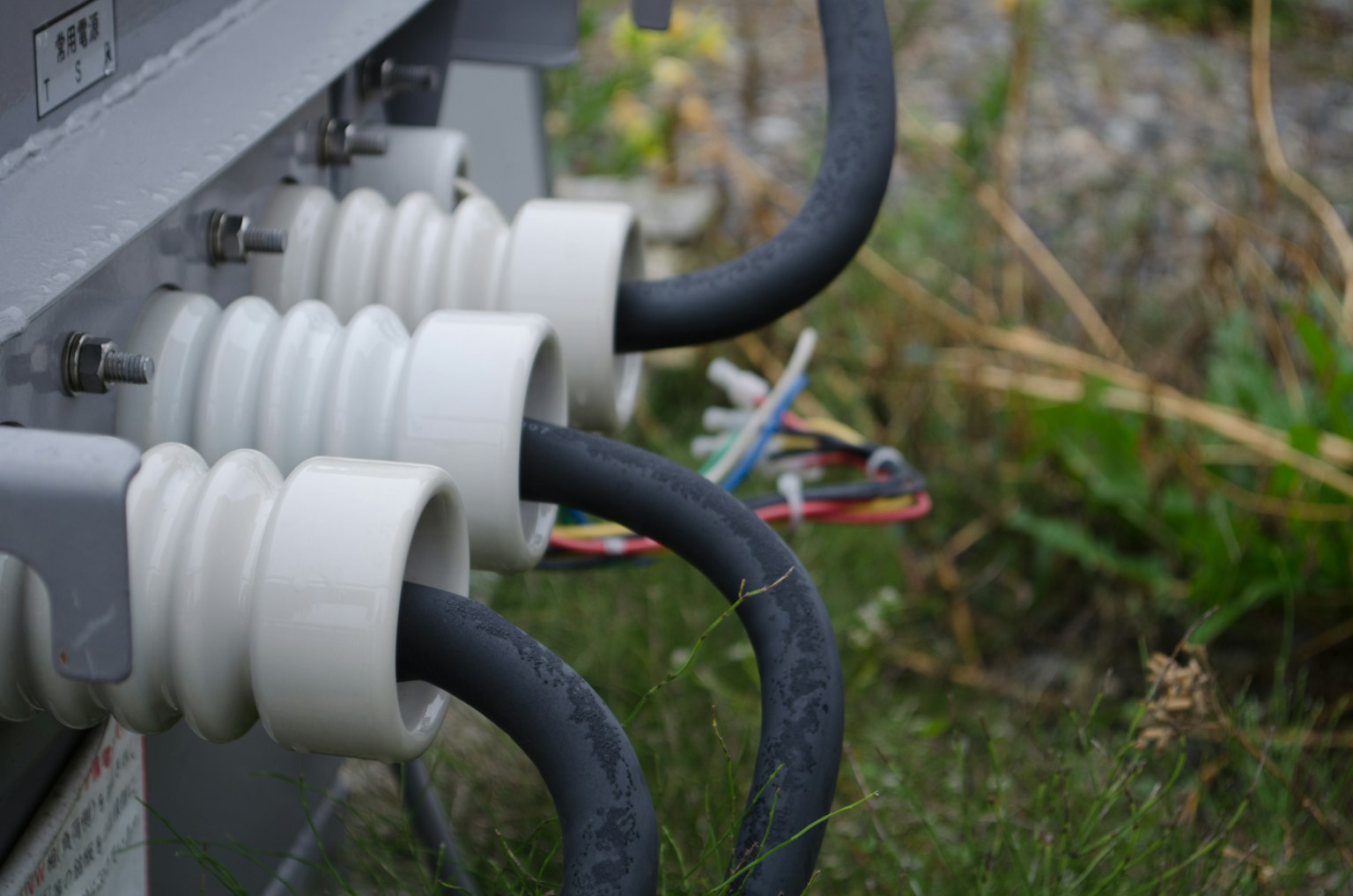 Câbles noirs multiples connectés à un équipement électrique avec des isolateurs blancs
