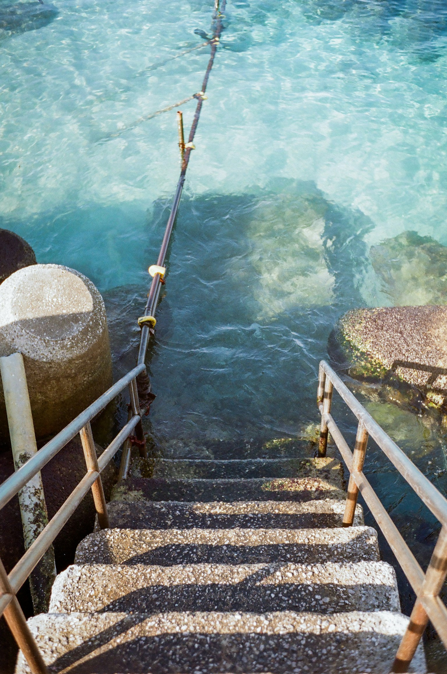 Steinstufen, die zu ruhigem blauen Wasser mit Holzgeländer führen