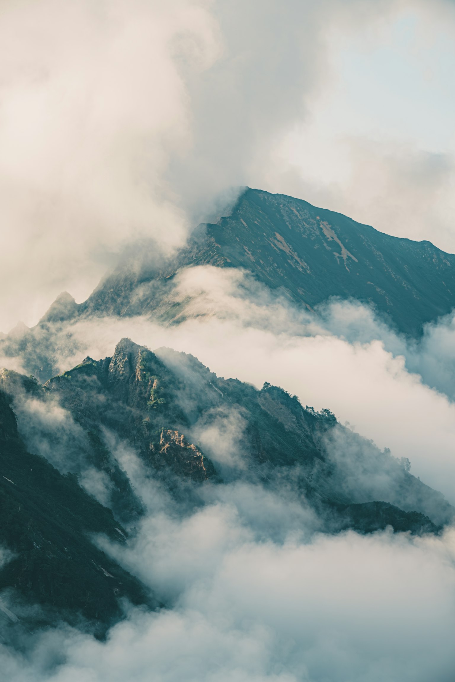 被云覆盖的山景，山顶升起的雾气营造出神秘的氛围