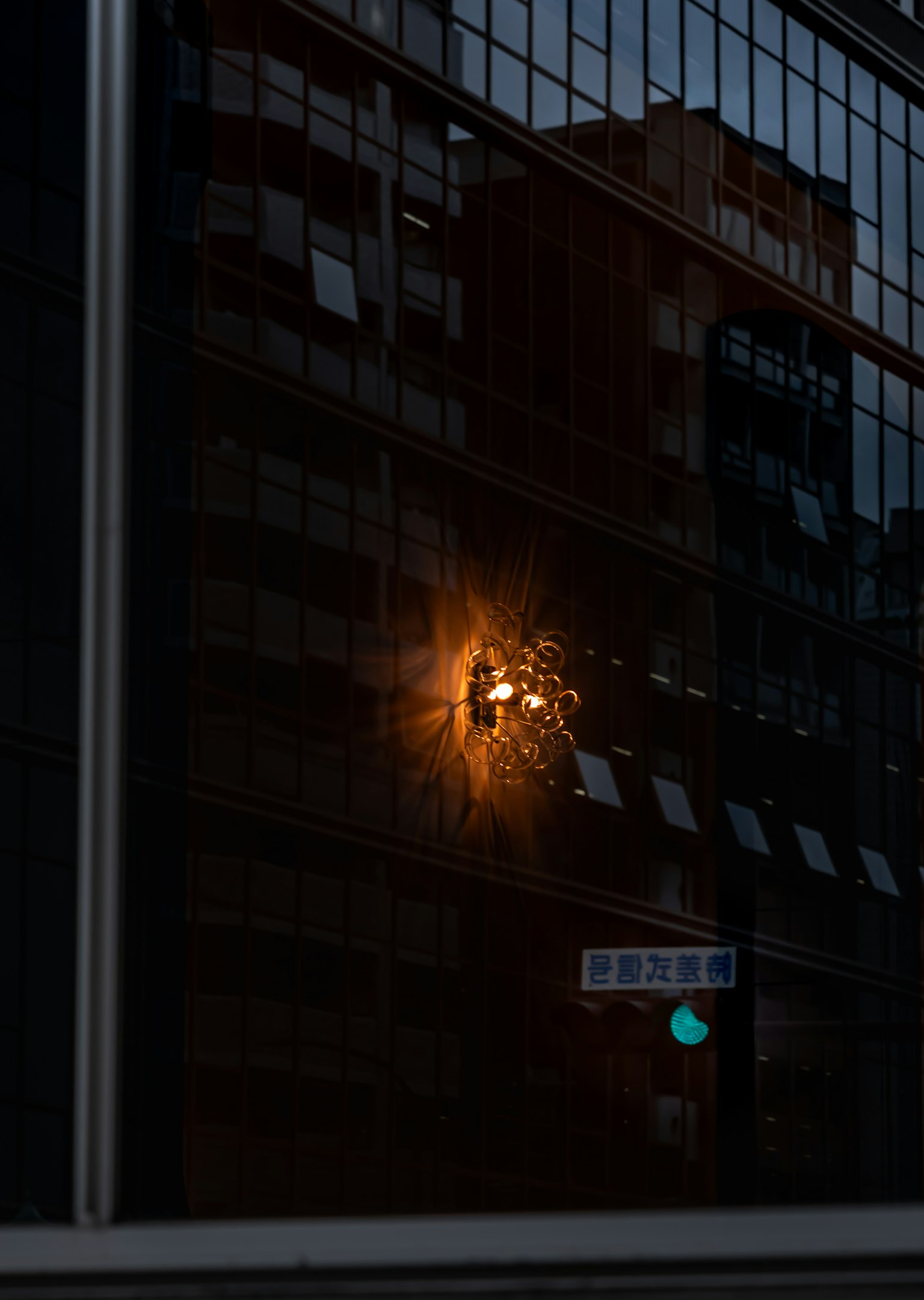 Reflection of city buildings in a window with an orange light