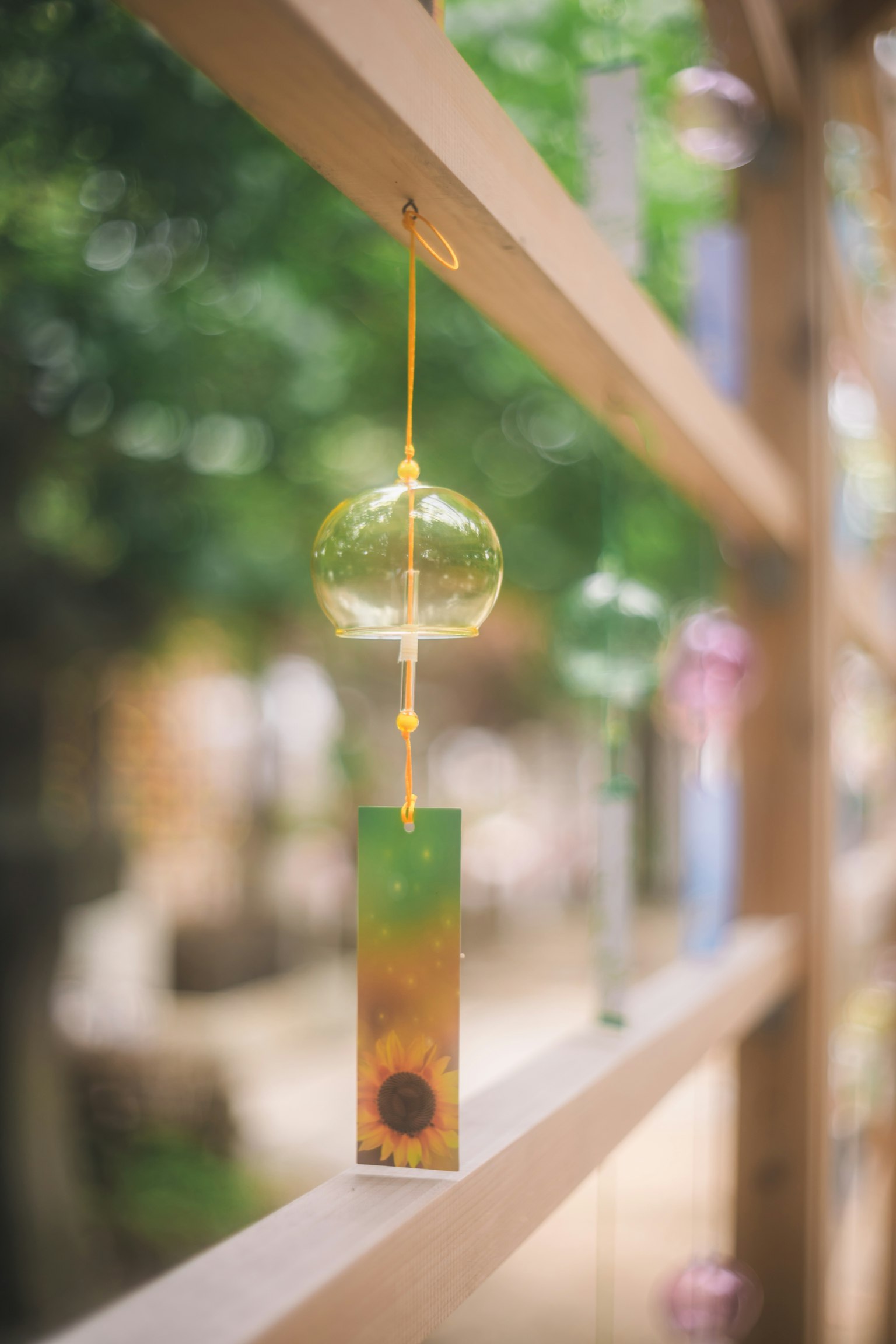 A wind chime hanging from a wooden lattice with a green background