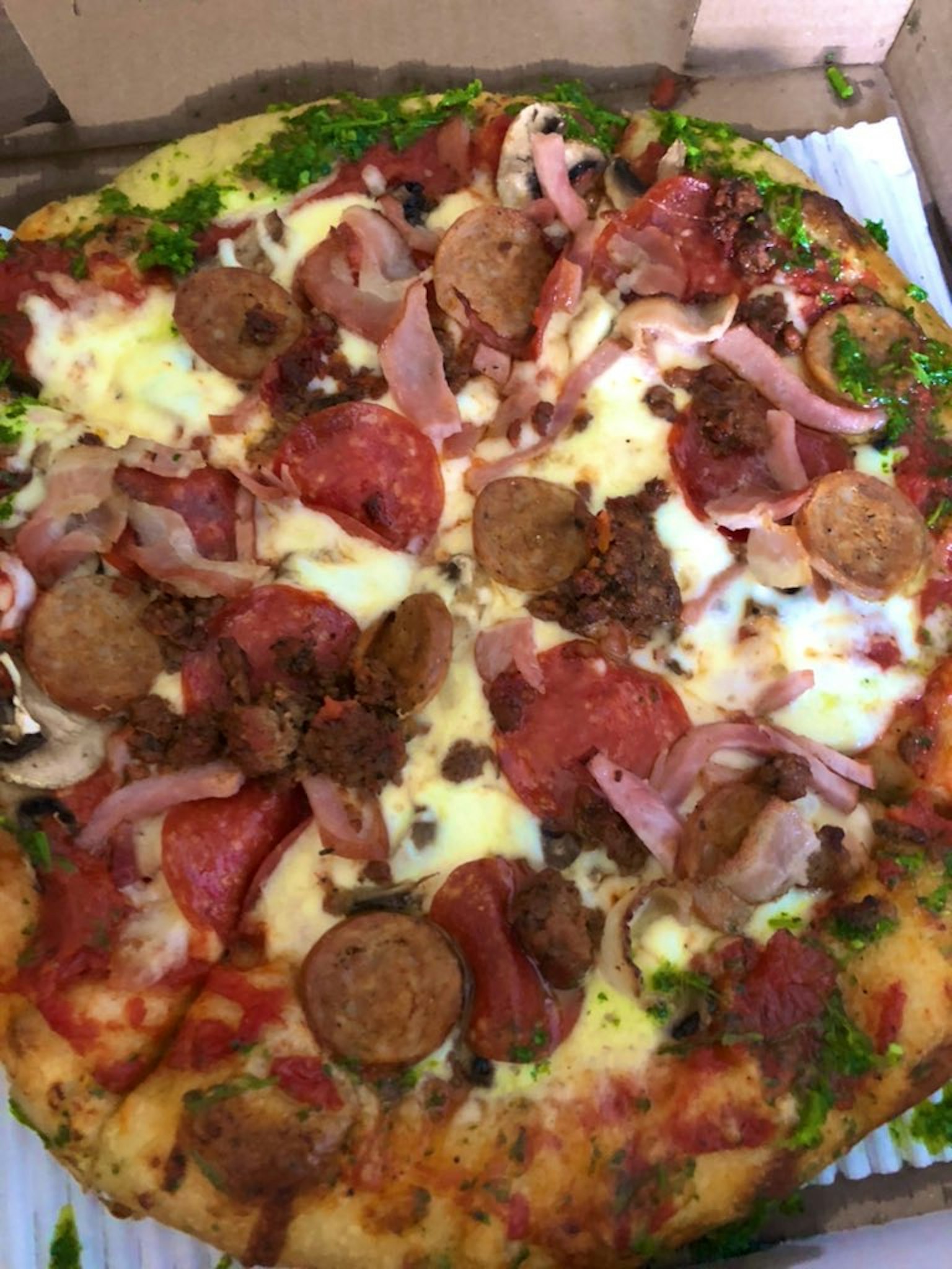 Delicious pizza topped with cheese sausage ham and vegetables