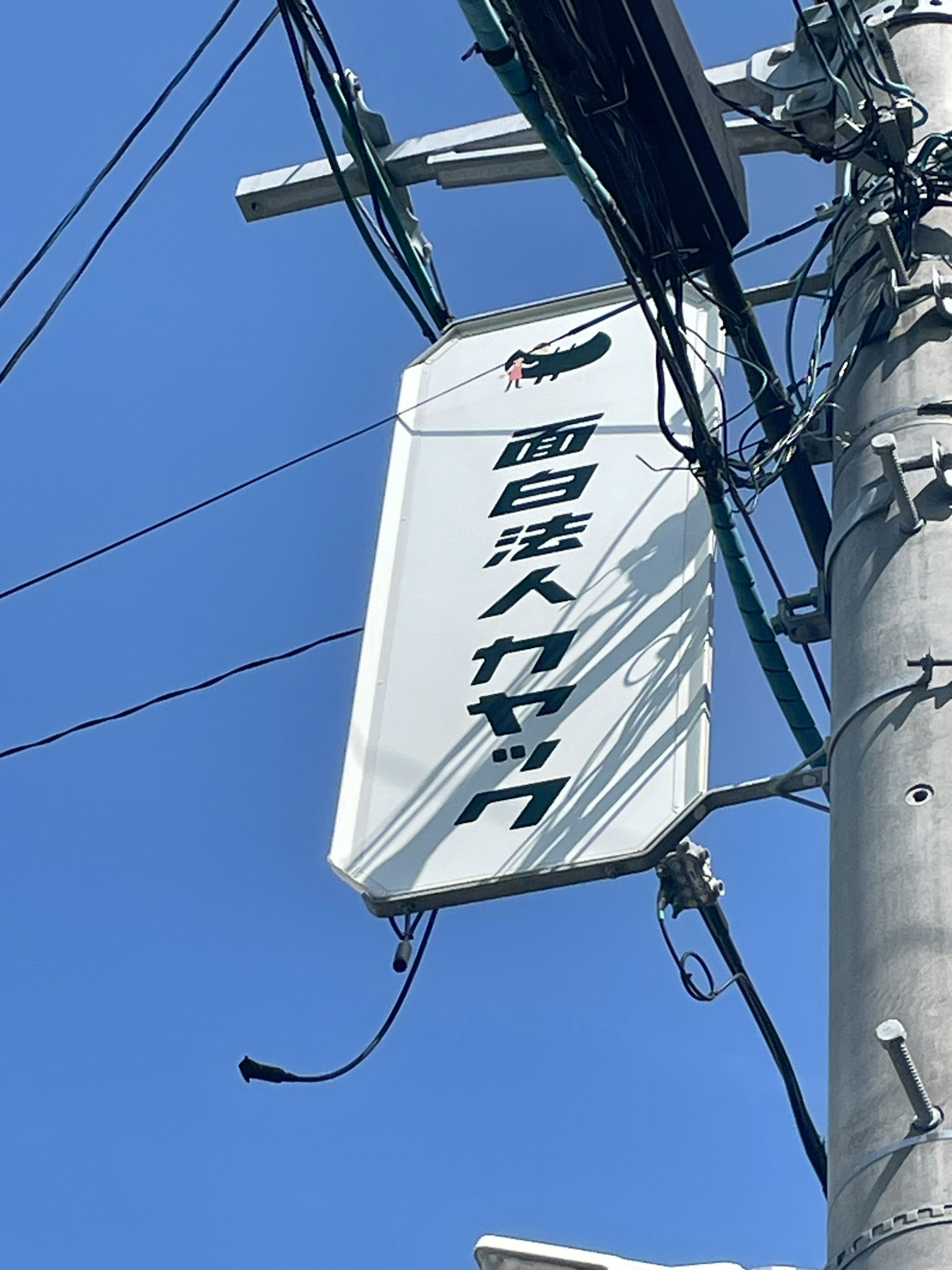 Weißes Schild an einem Strommast unter einem klaren blauen Himmel
