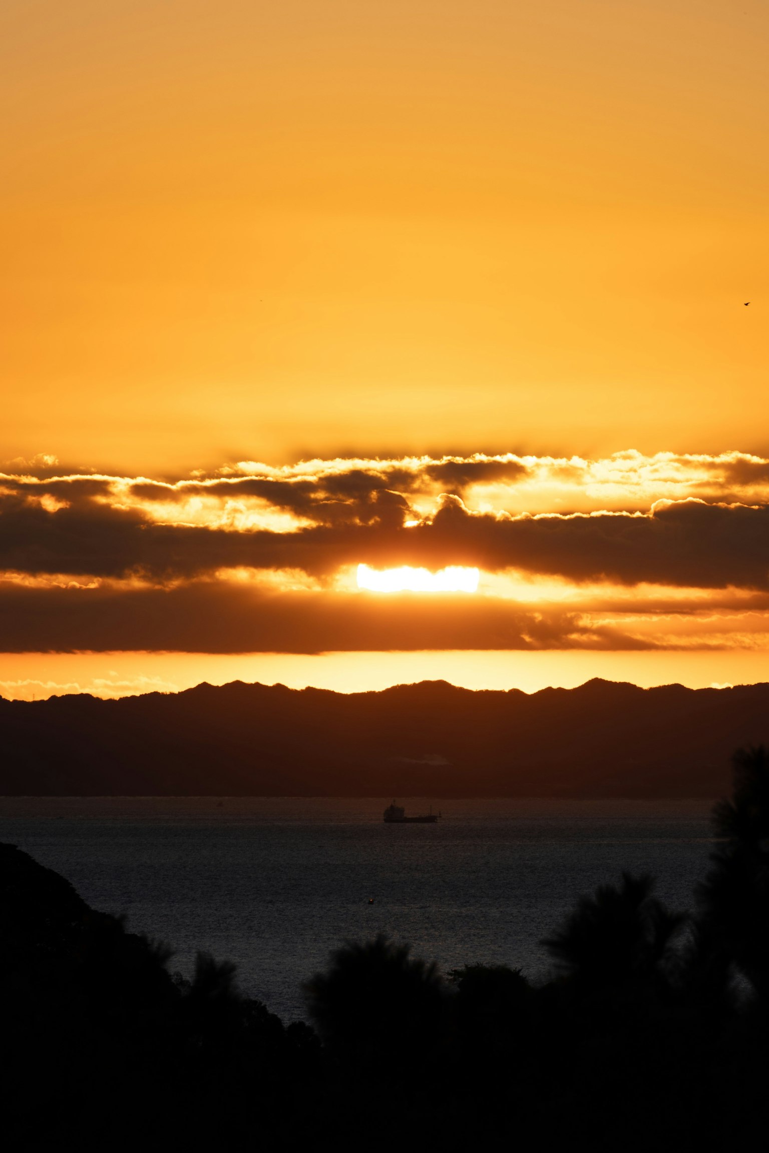 Coucher de soleil sur l'océan avec des nuages colorés et la silhouette des montagnes