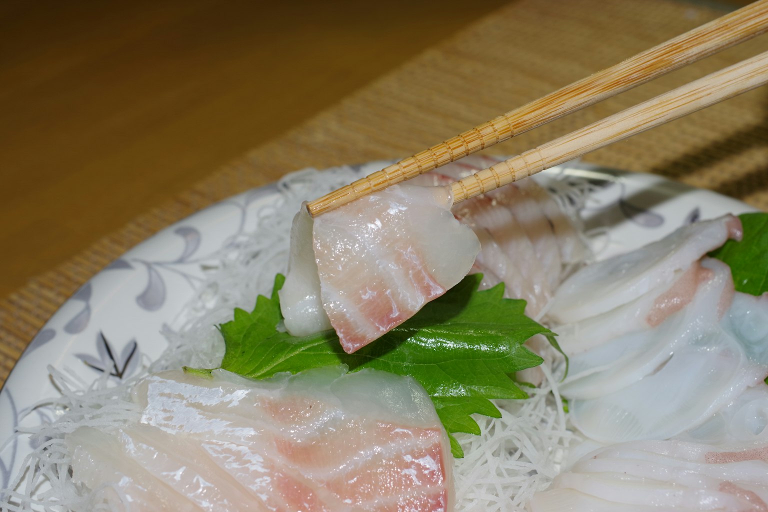 Sashimi segar disajikan di piring dengan daun shiso