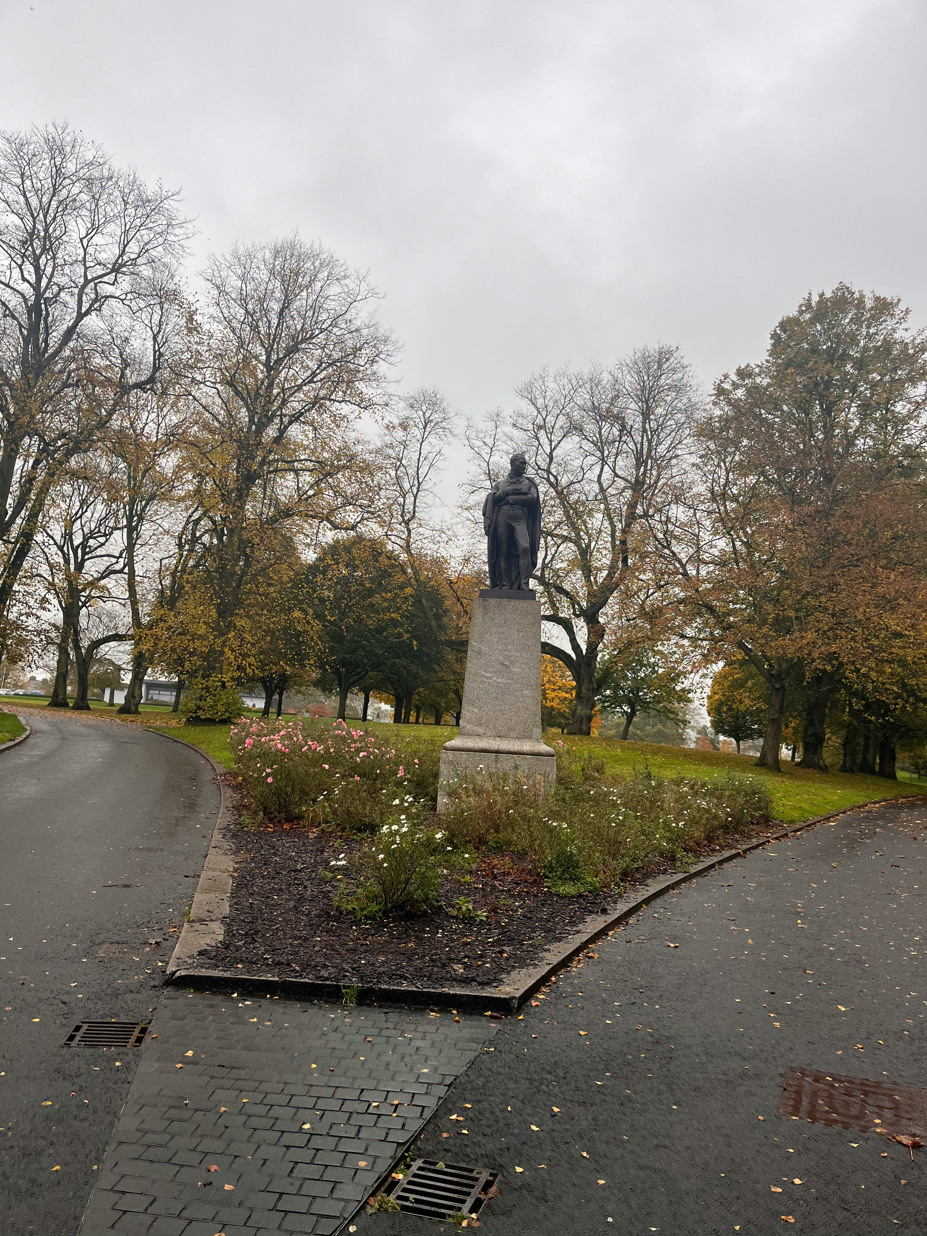 Parkweg mit einer Statue auf einem Sockel