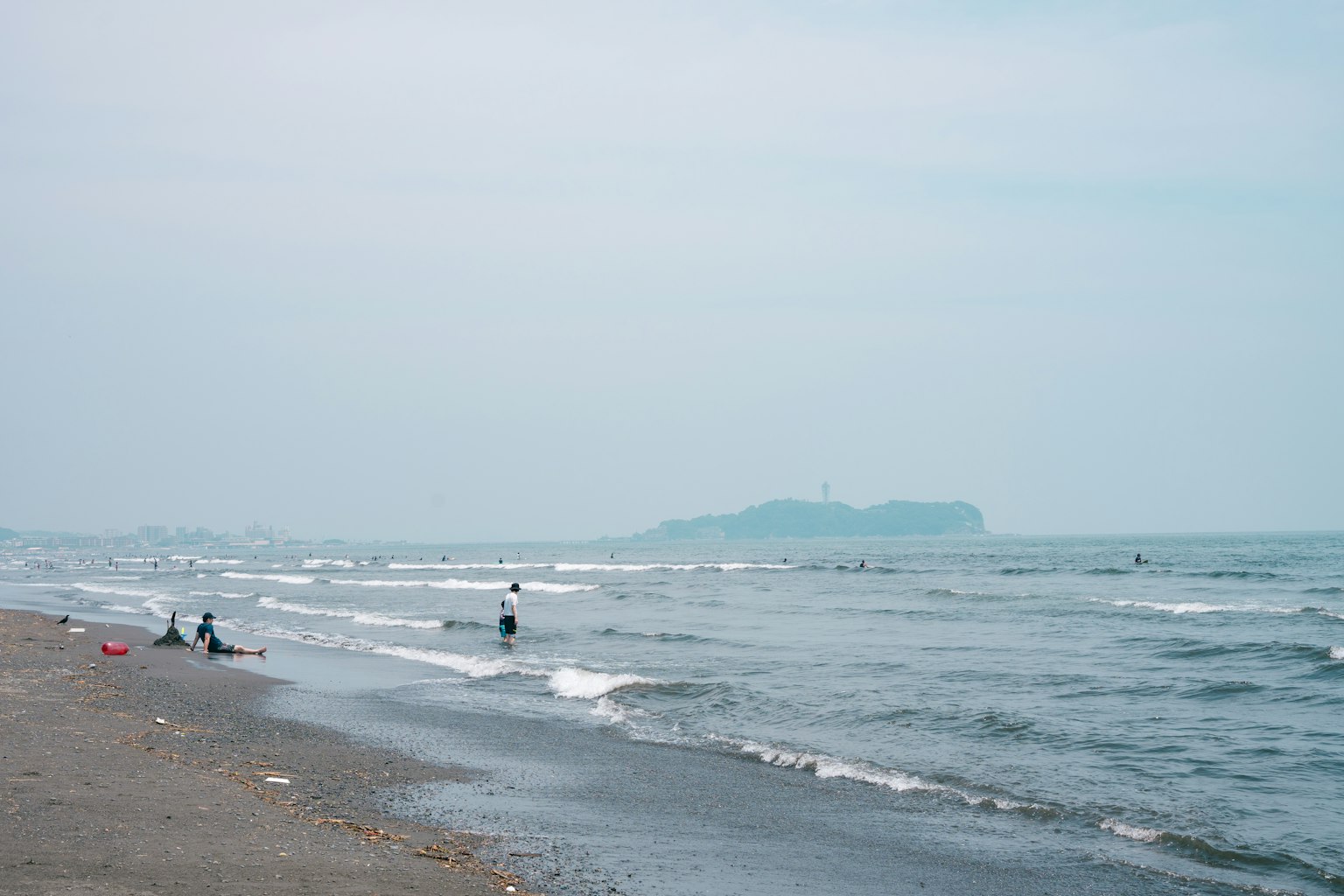 Scena di spiaggia tranquilla con onde leggere e un'isola in lontananza