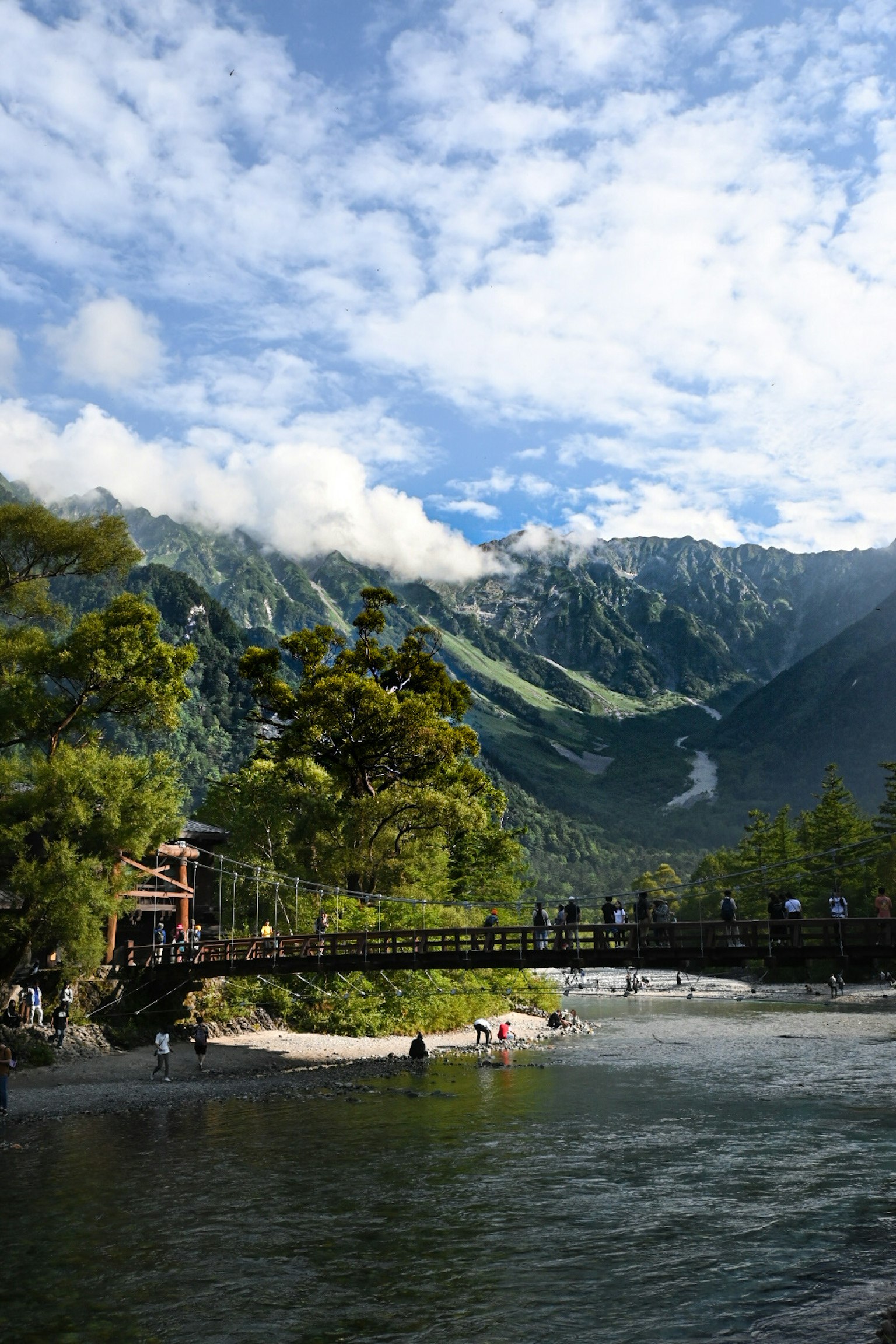 Malerei von Bergen und Fluss mit einer Holzbrücke