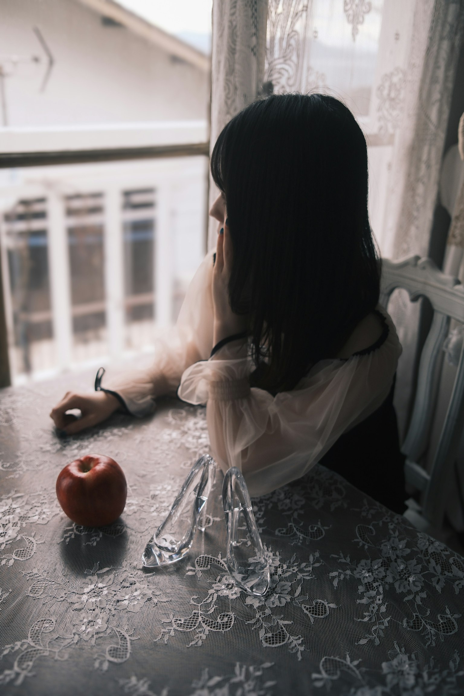 窓辺で考え込む女性とテーブルに置かれた赤いリンゴ