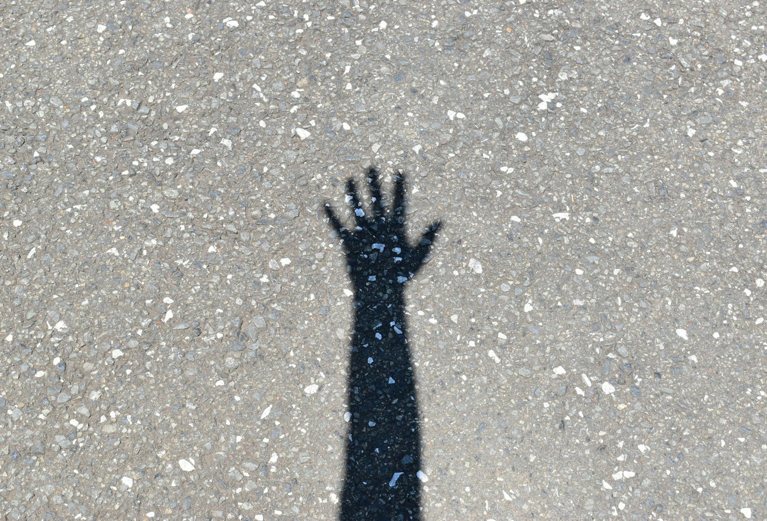 A shadow of a raised hand on the ground
