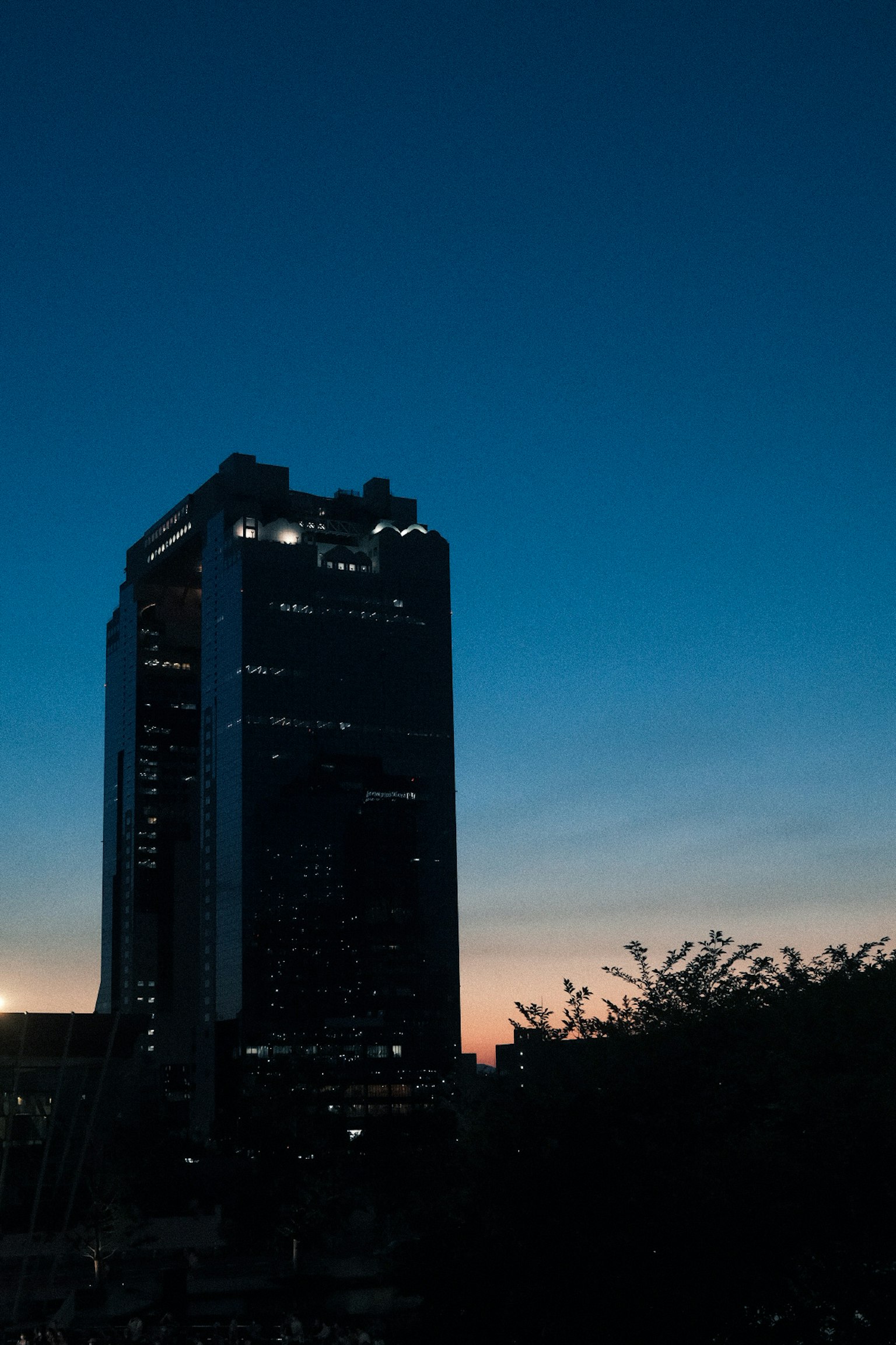 Silhouette of a skyscraper against a twilight sky with sunset hues