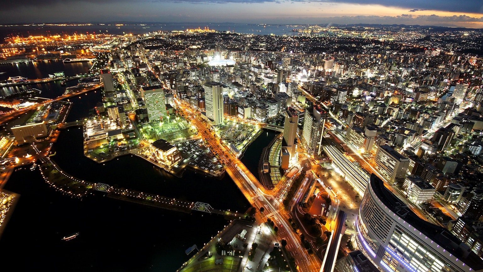 Vista panoramica di una città vibrante di notte con grattacieli illuminati e ponti