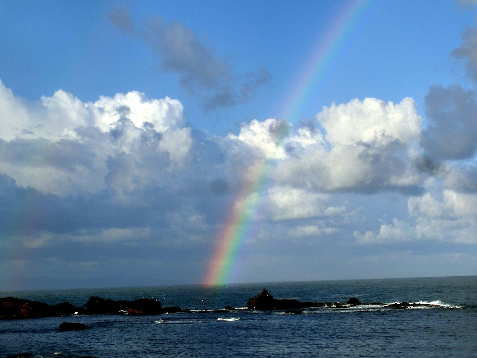 海岸景觀上方有彩虹和雲彩