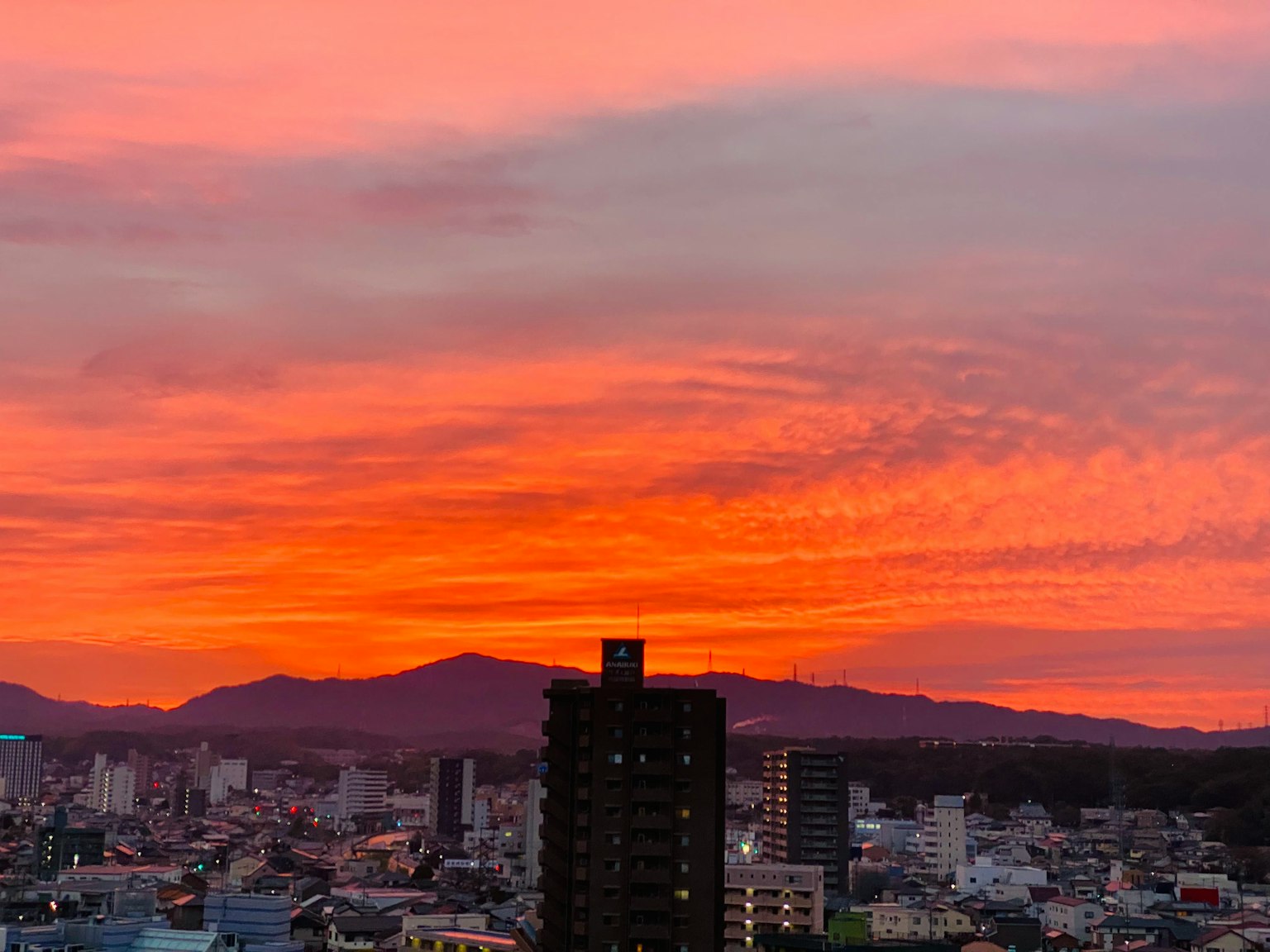 Wunderschöner Sonnenuntergang über einer Stadtlandschaft mit Hochhäusern und Bergen im Hintergrund