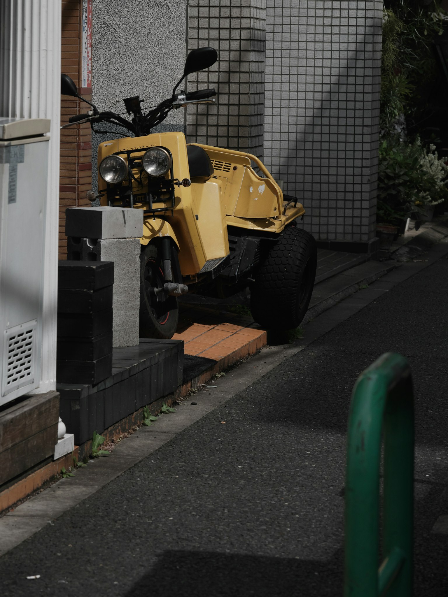 一輛停在狹窄巷道中的黃色三輪車
