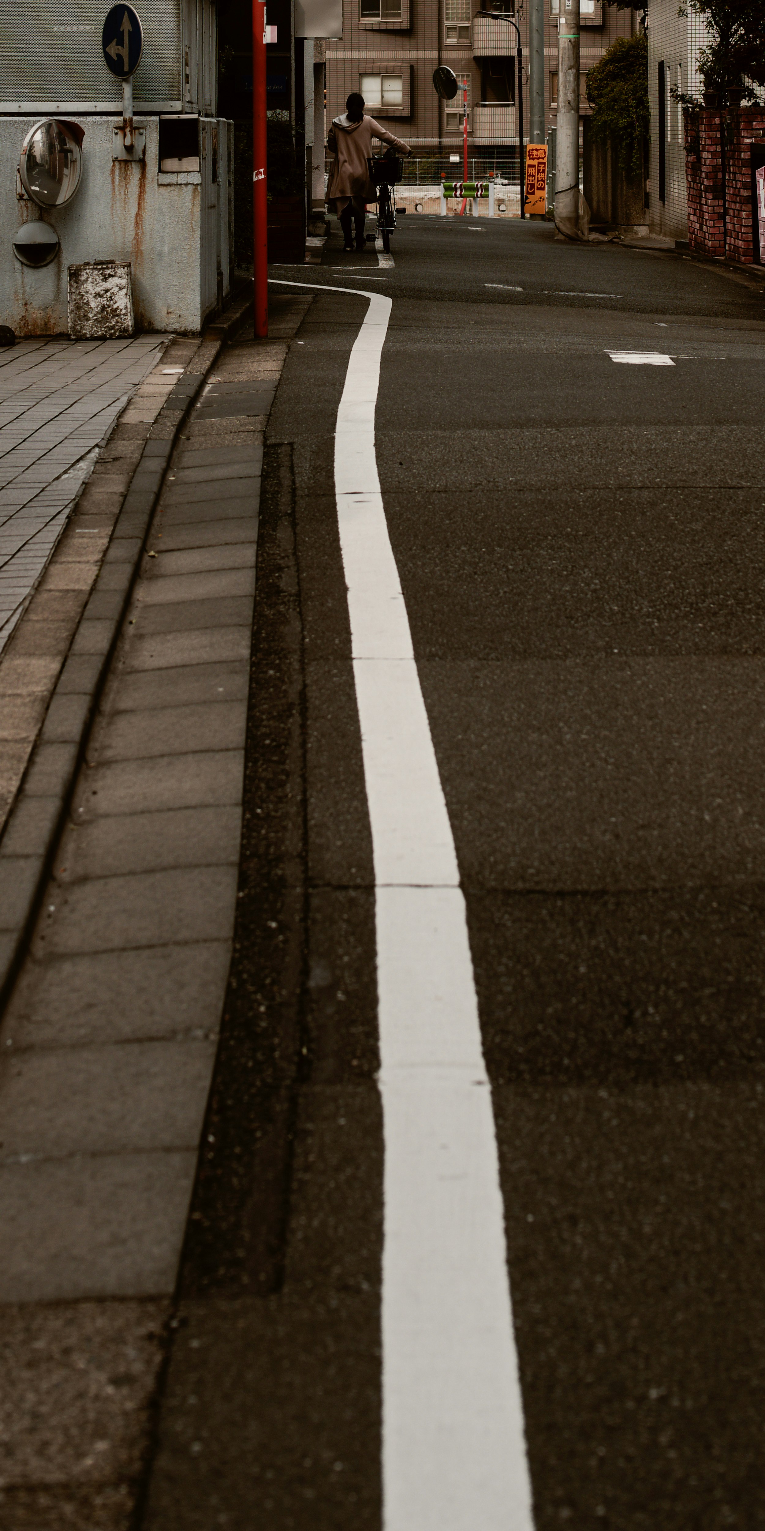 白線の先の路地に続く自転車のある街並み