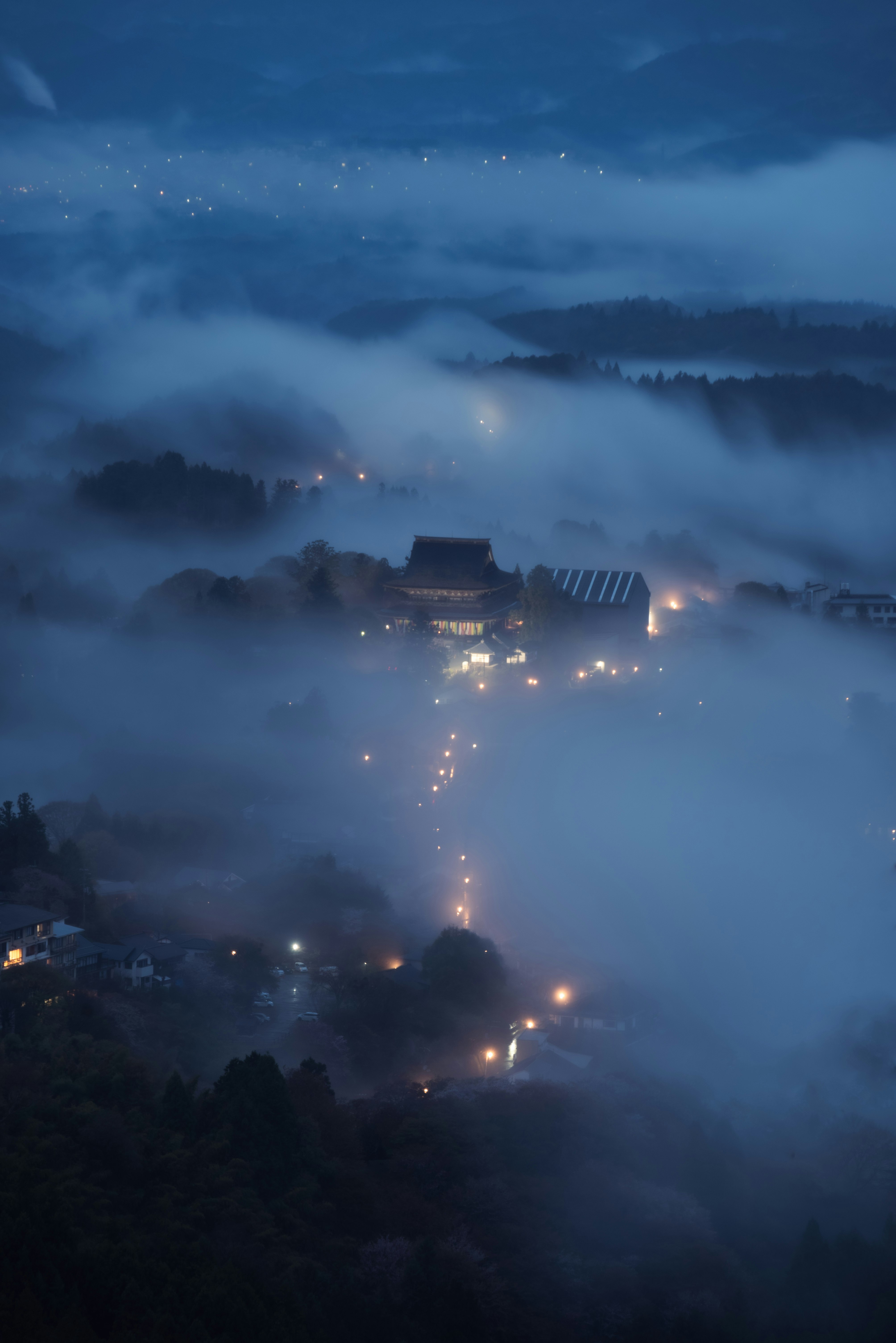霧に包まれた夜の山あいの集落と灯り