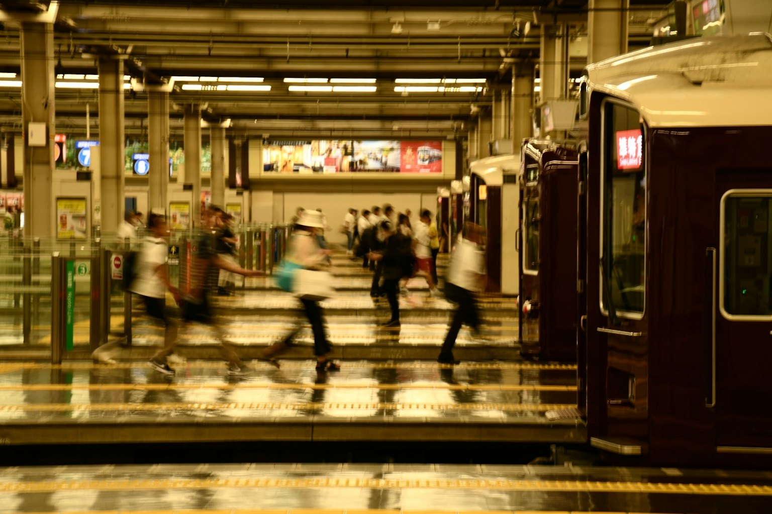 Plataforma de estación de tren concurrida con pasajeros borrosos y un tren