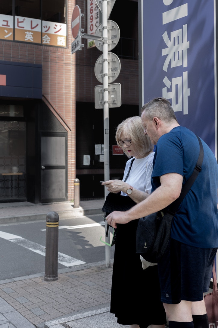 a couple looking at a smartphone on a city street corner