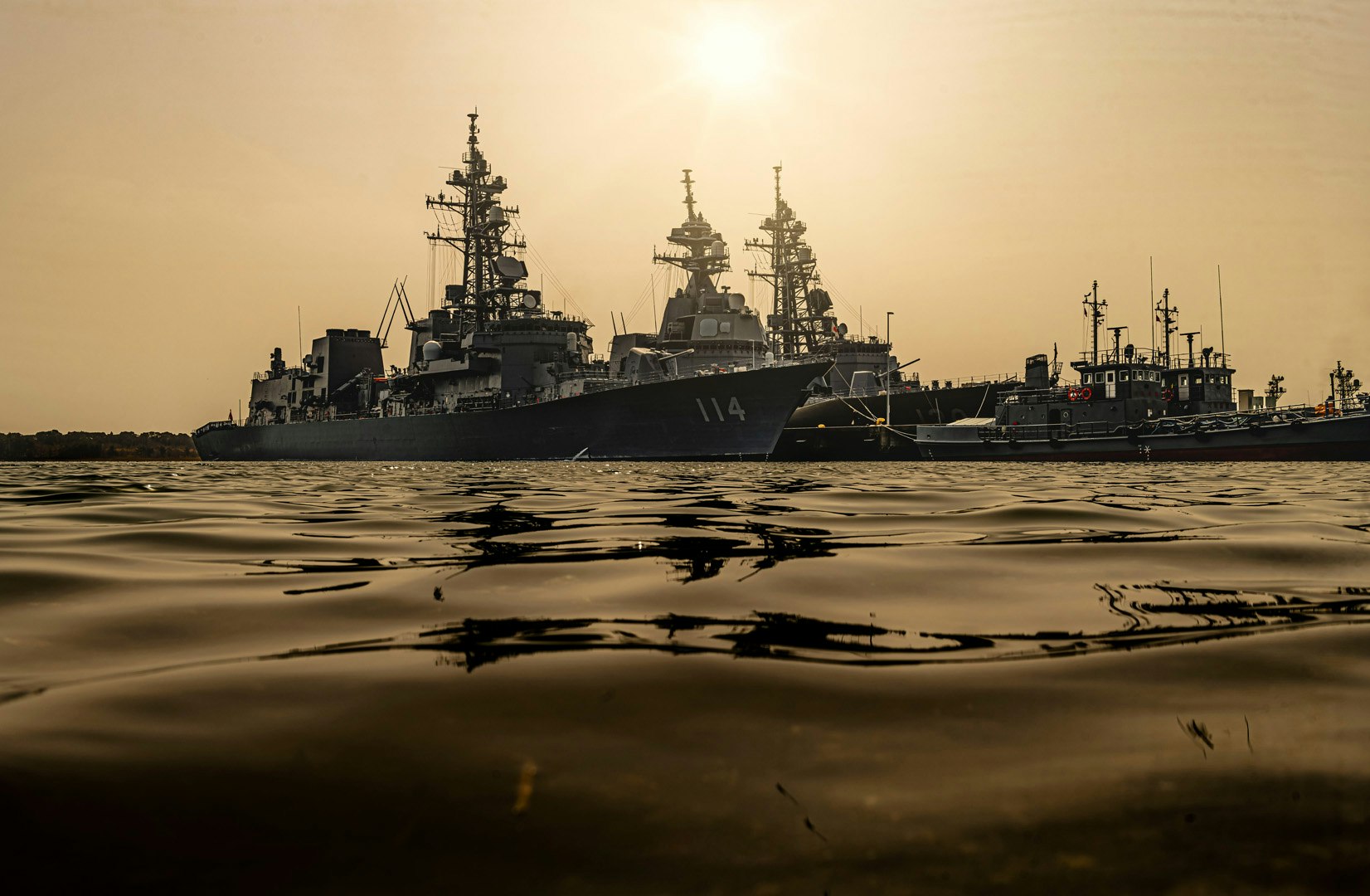 黃昏港口裡停泊的軍艦與海岸線景象
