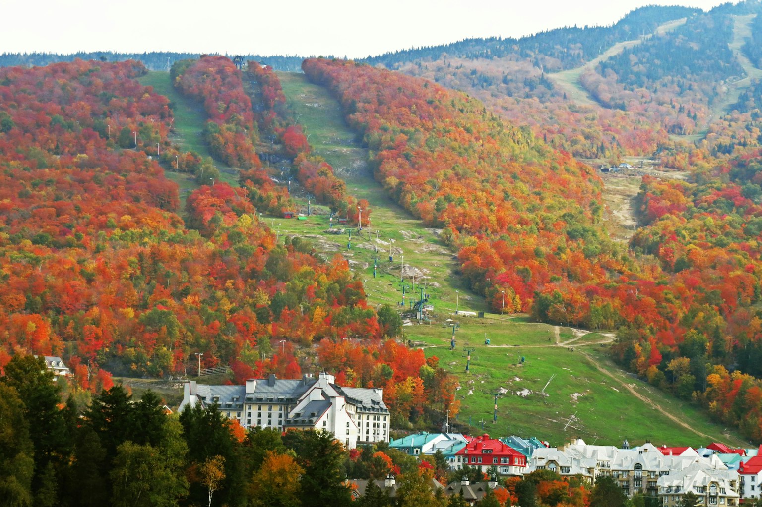 Paisaje montañoso rodeado de follaje otoñal colorido con edificios