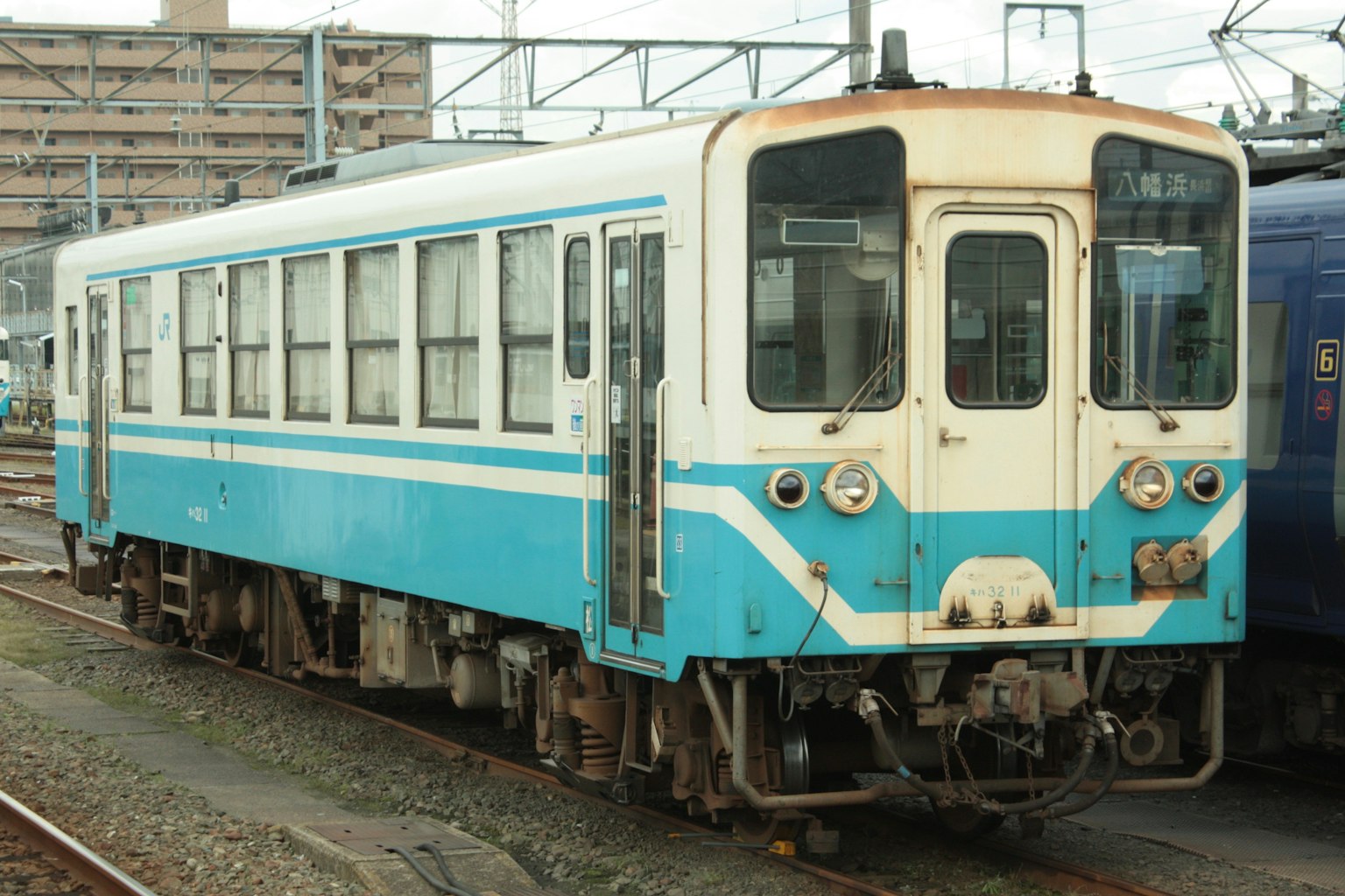 รถไฟสีน้ำเงินและสีขาวจอดอยู่บนรางรถไฟ