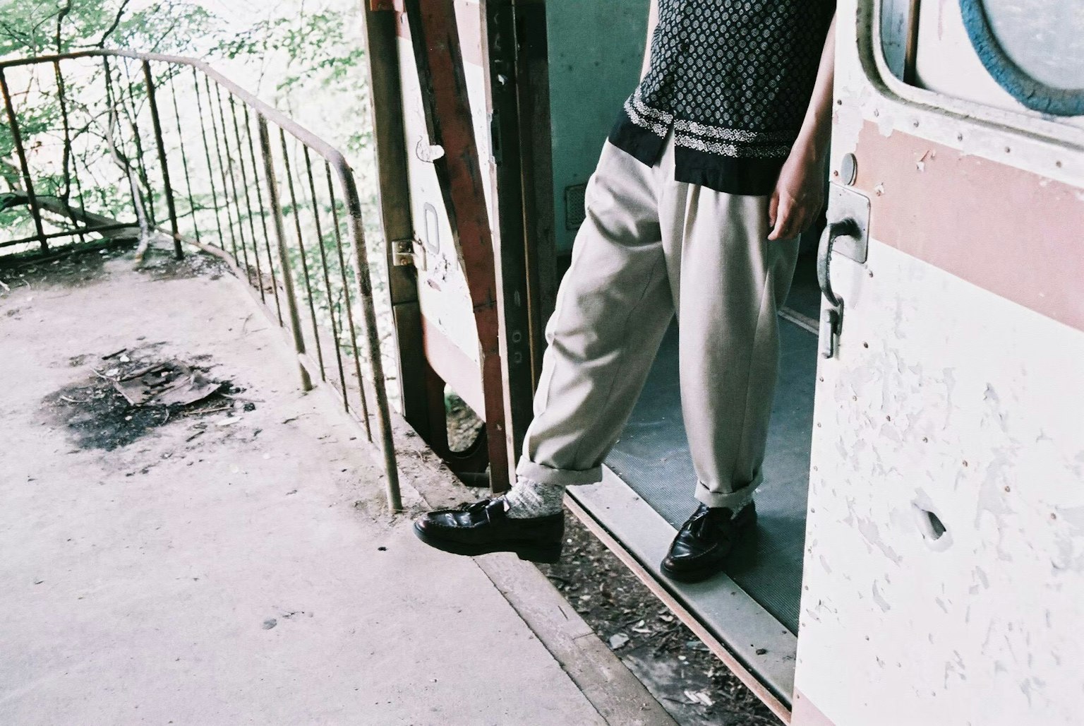 Person's feet standing at the door wearing light-colored pants and black shoes vintage environment