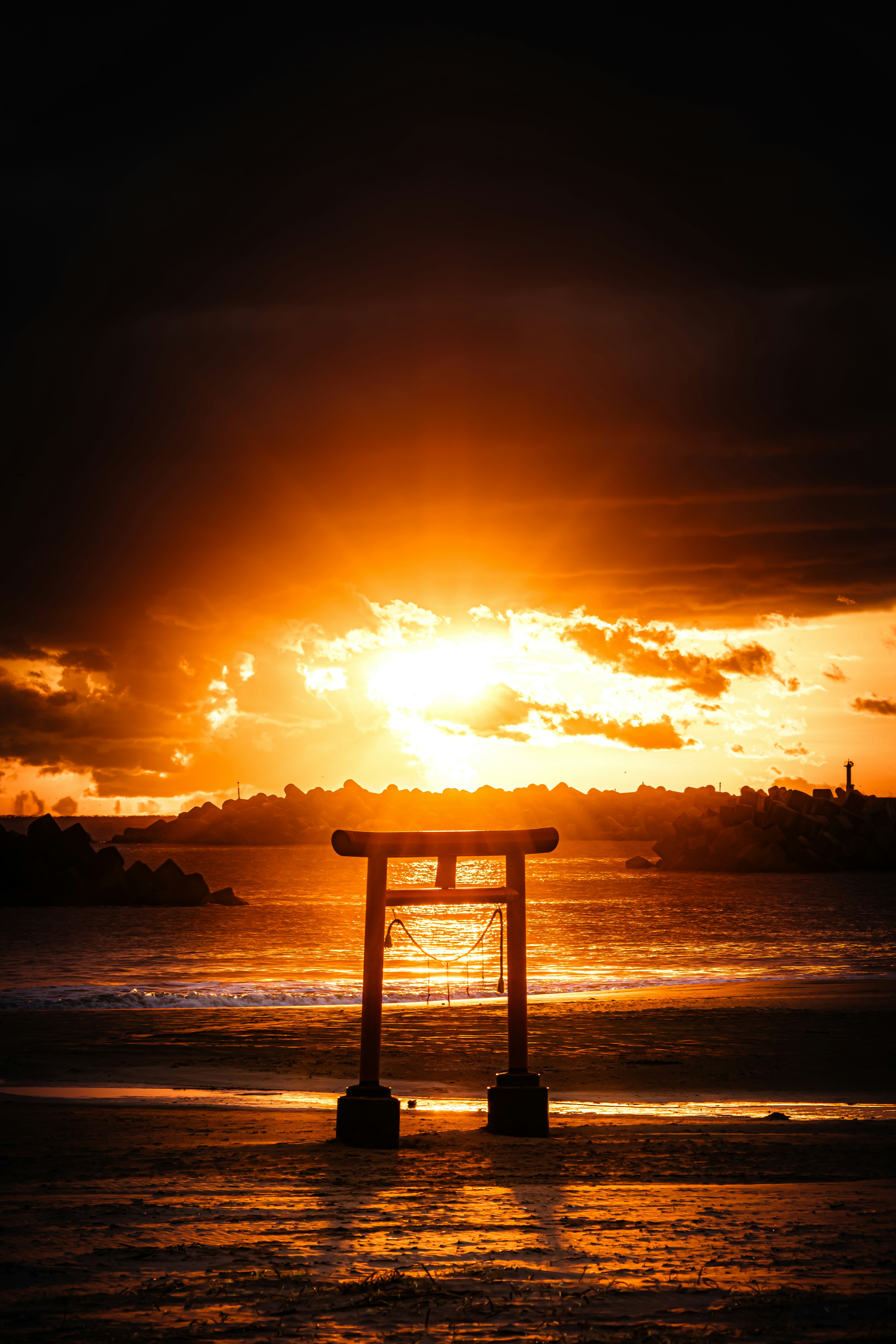 夕日に照らされる海辺の鳥居